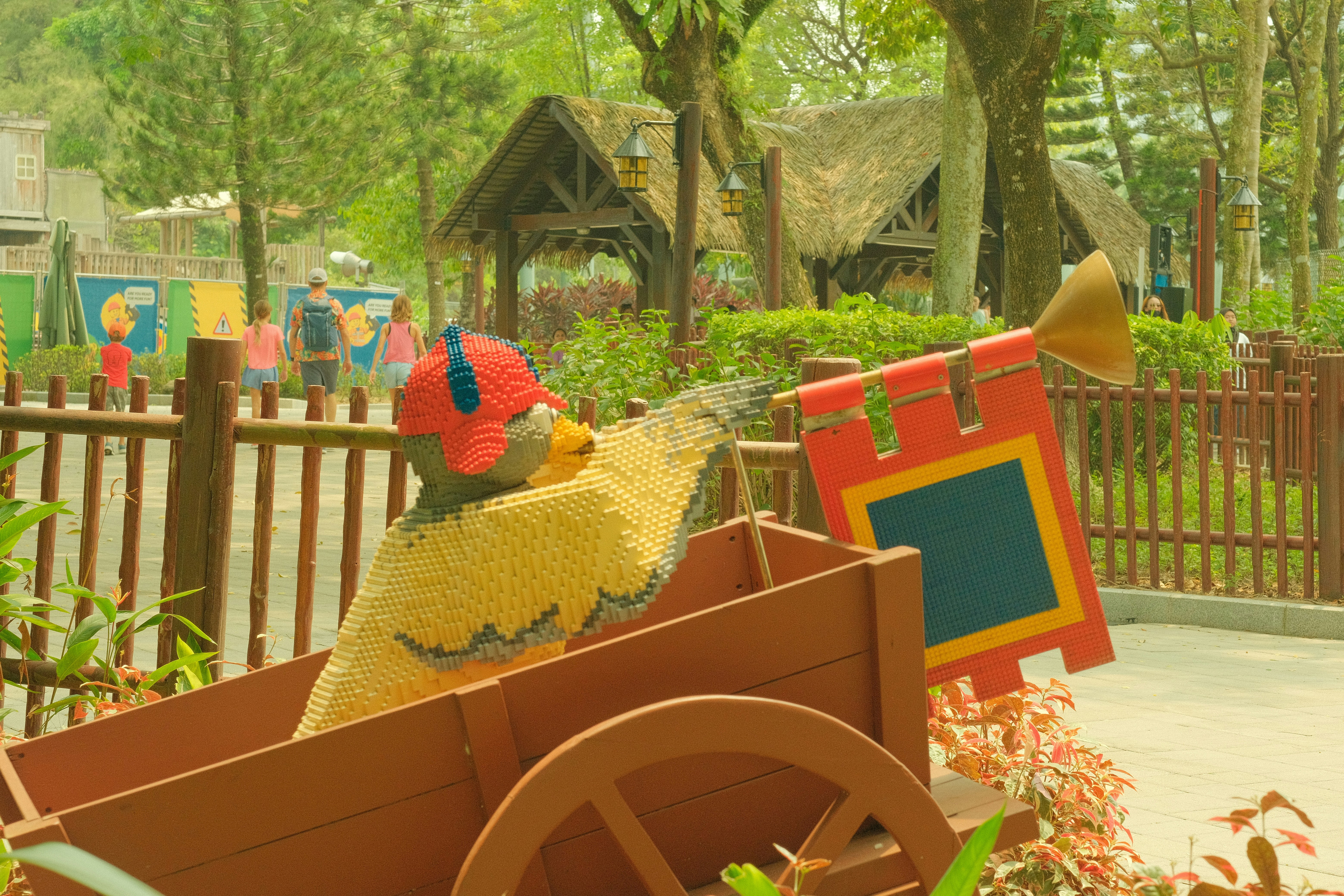 A Lego figure in a red cap holding a trumpet in a wooden cart