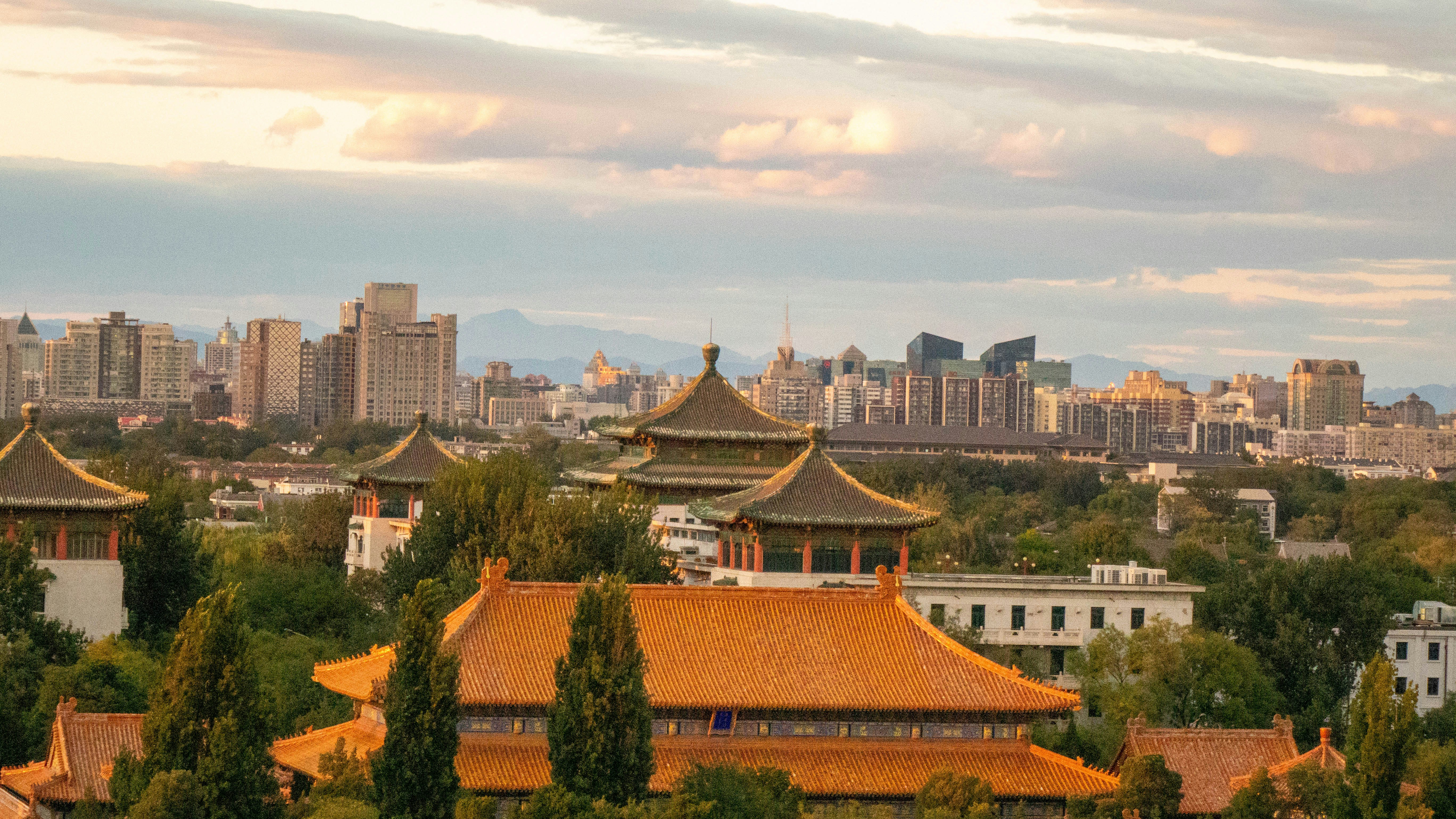 Traditional Chinese architecture with orange tiled roofs before a modern city skyline in Beijing