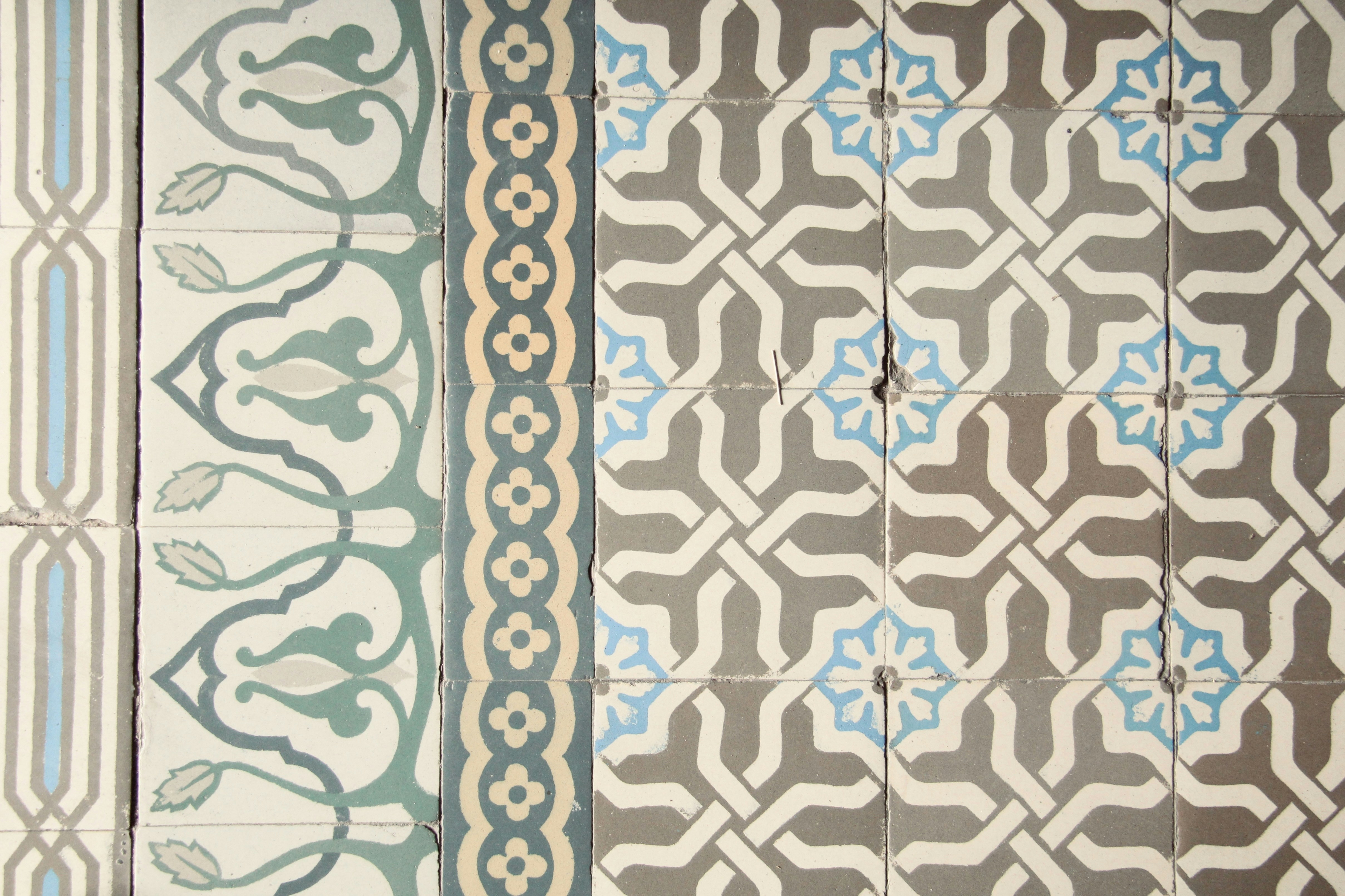 A pattern of vintage ceramic tiles with blue and grey geometric and floral motifs