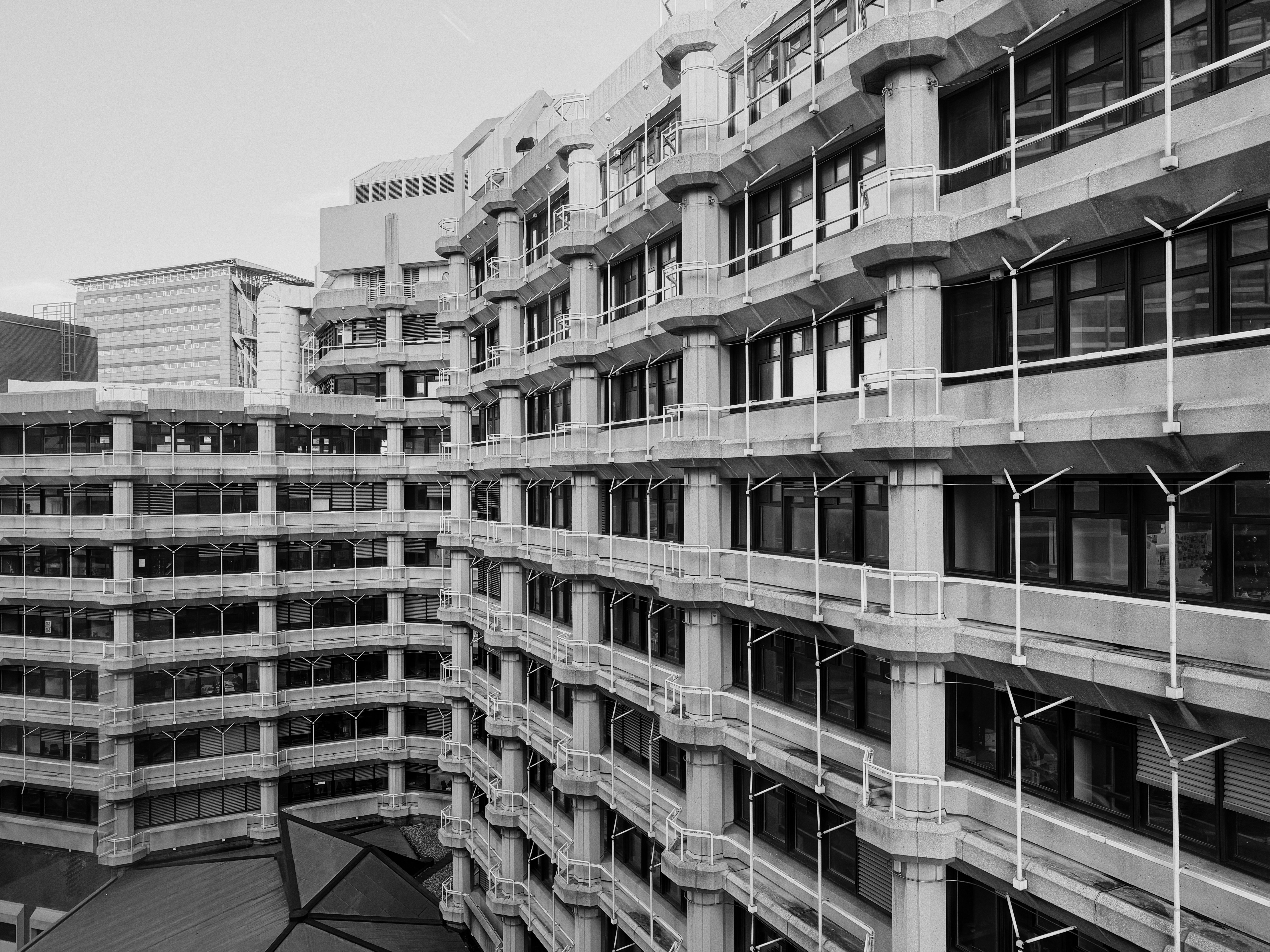 Ein brutalistisches Bürogebäude aus Beton mit sich wiederholenden modularen Balkonen und dunklen Fenstern