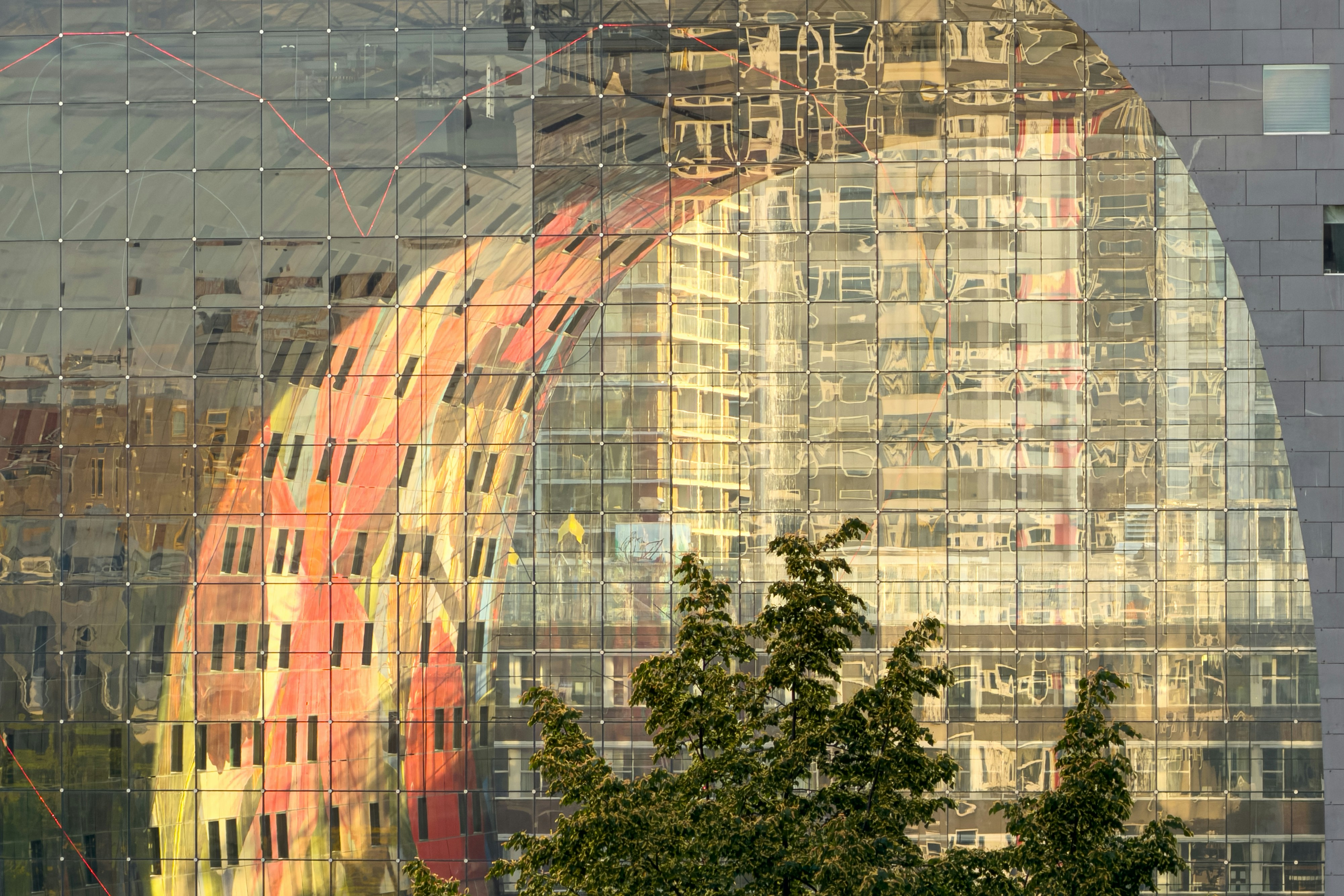 Spiegelungen von Stadtgebäuden und ein farbenfrohes Wandbild auf einer modernen Glasfassade