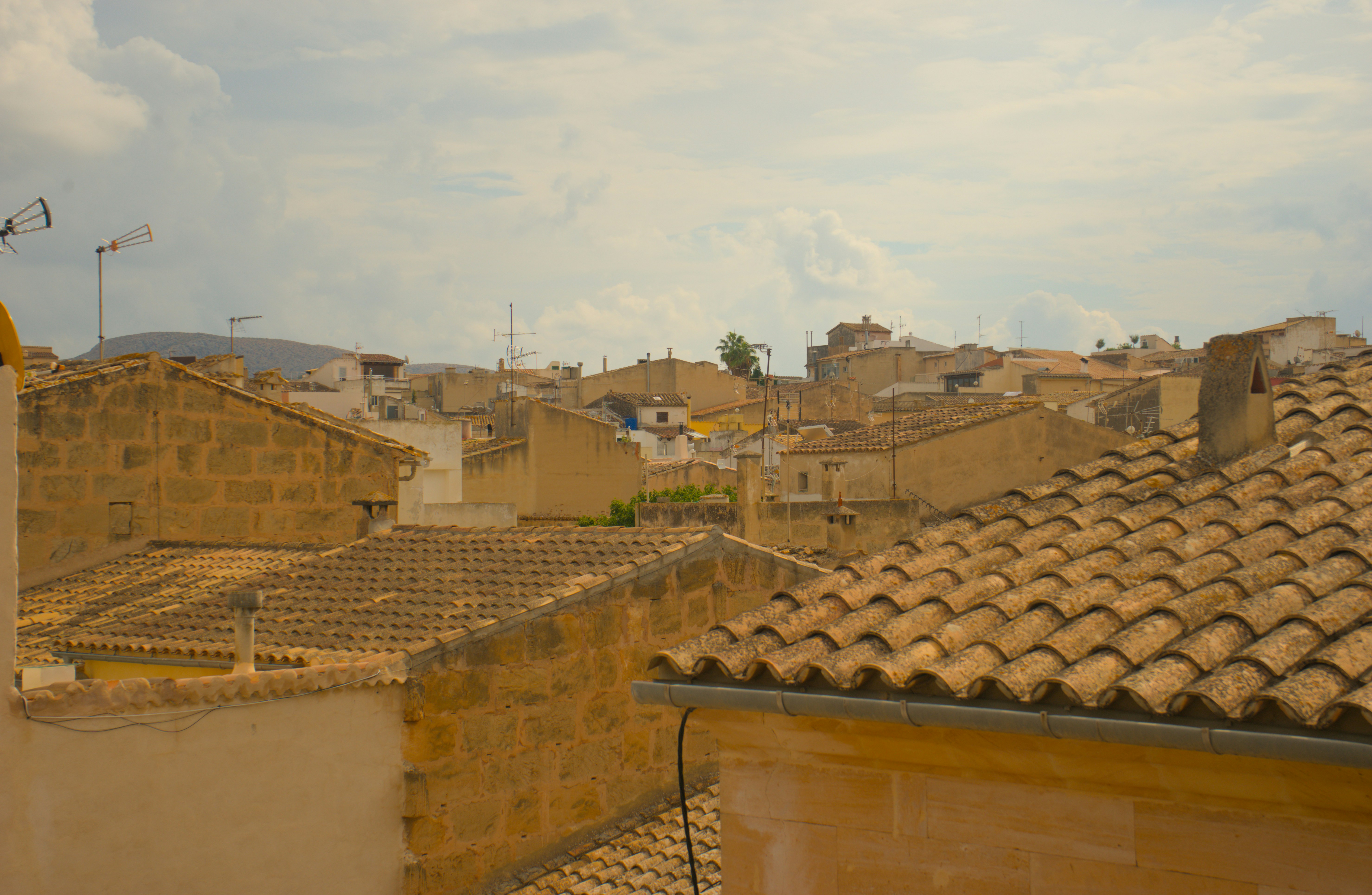 A view of terracotta tiled roofs and stone buildings under a cloudy sky