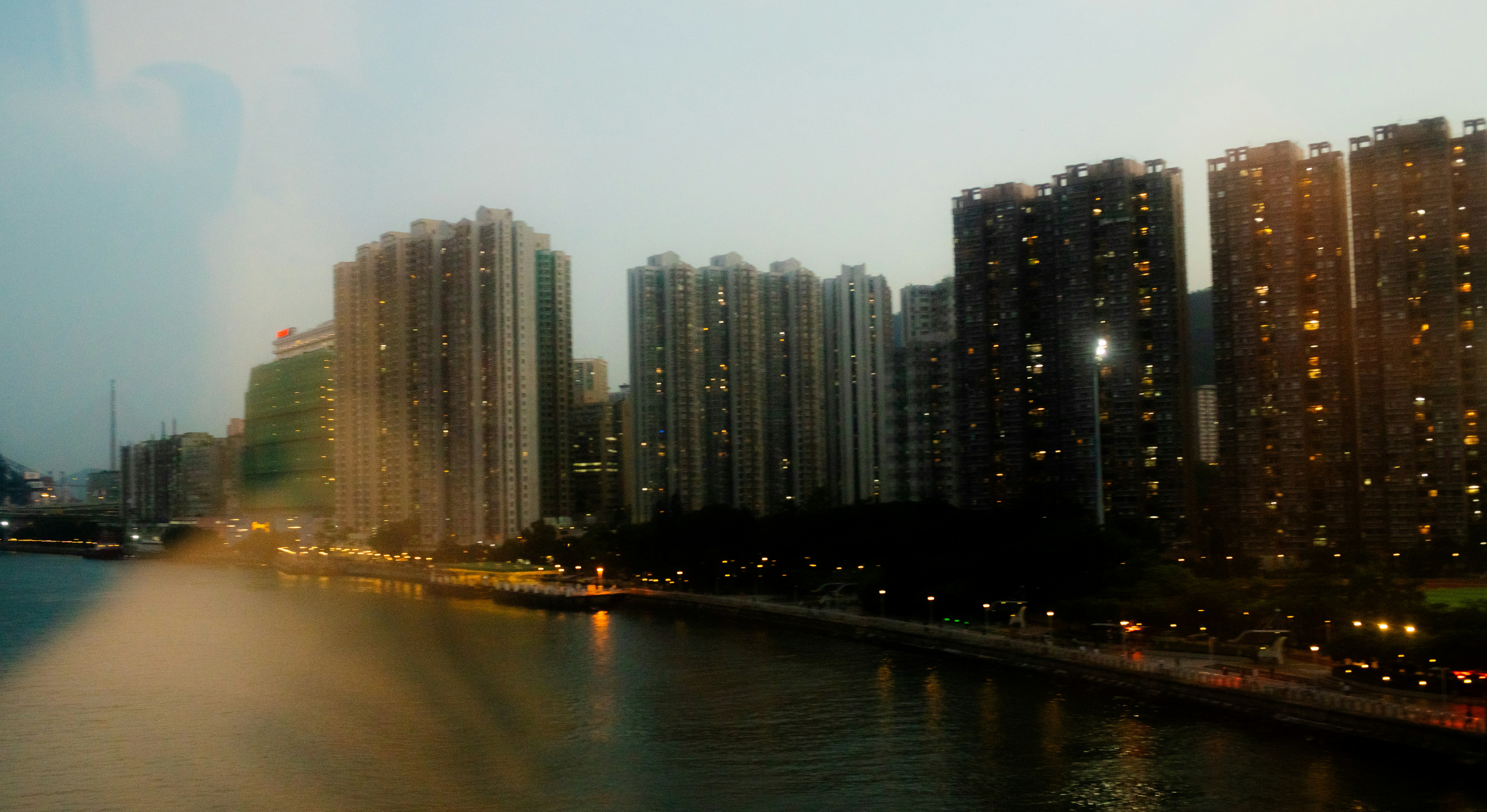 Tall residential apartment towers along a waterfront at dusk with glowing windows