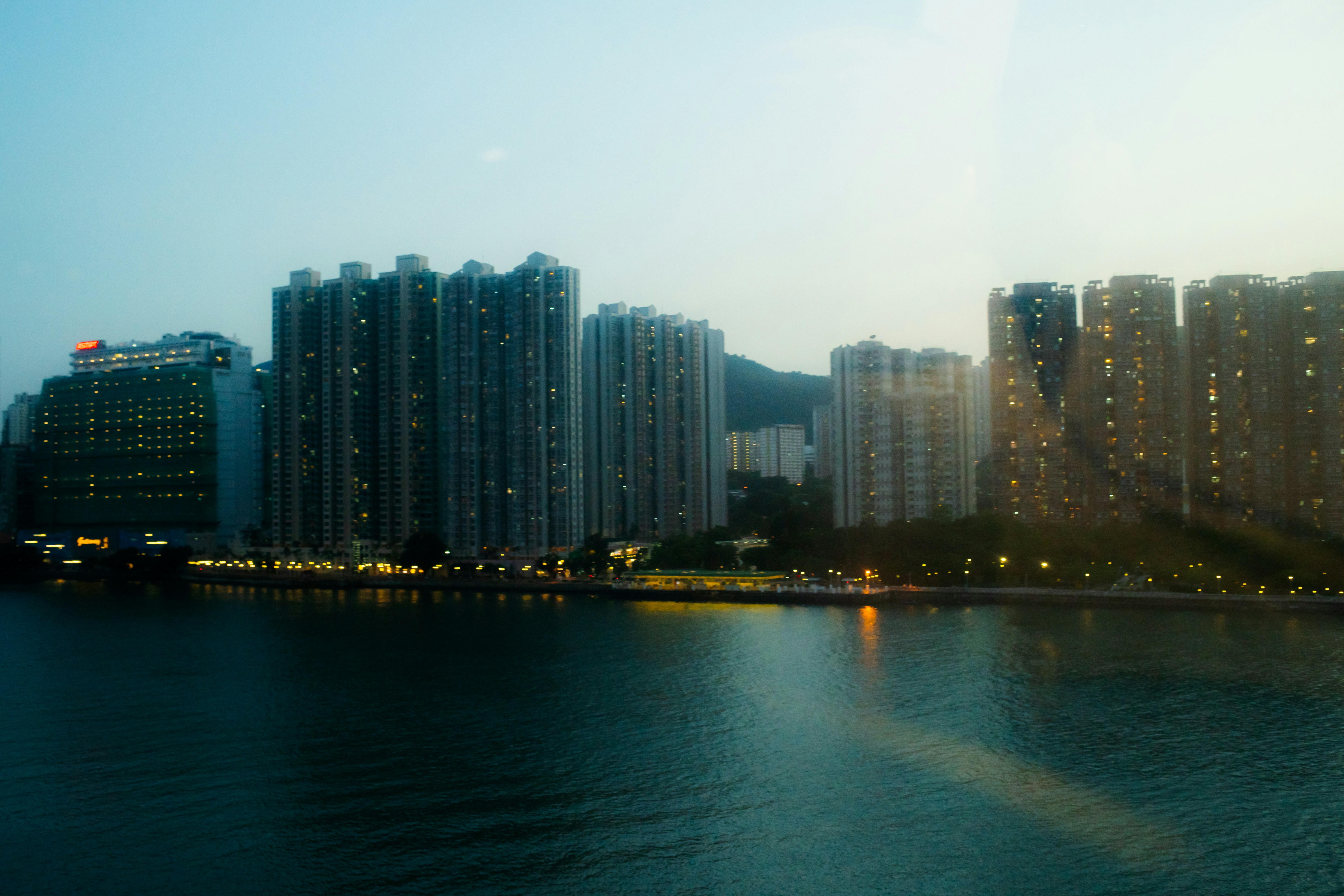 Tall residential apartment buildings along a waterfront at low sun