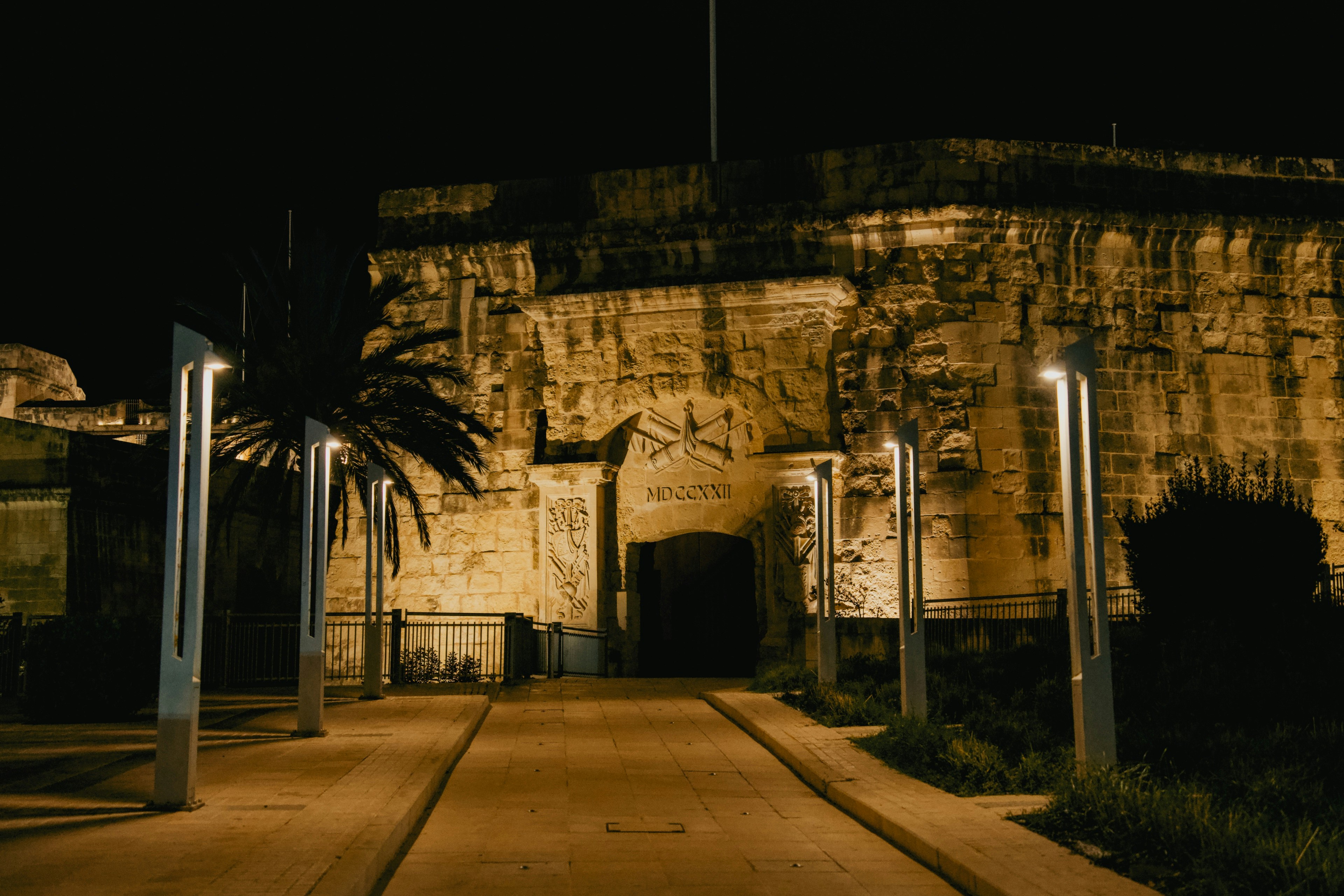 A stone fortress gate illuminated by modern street lamps at night