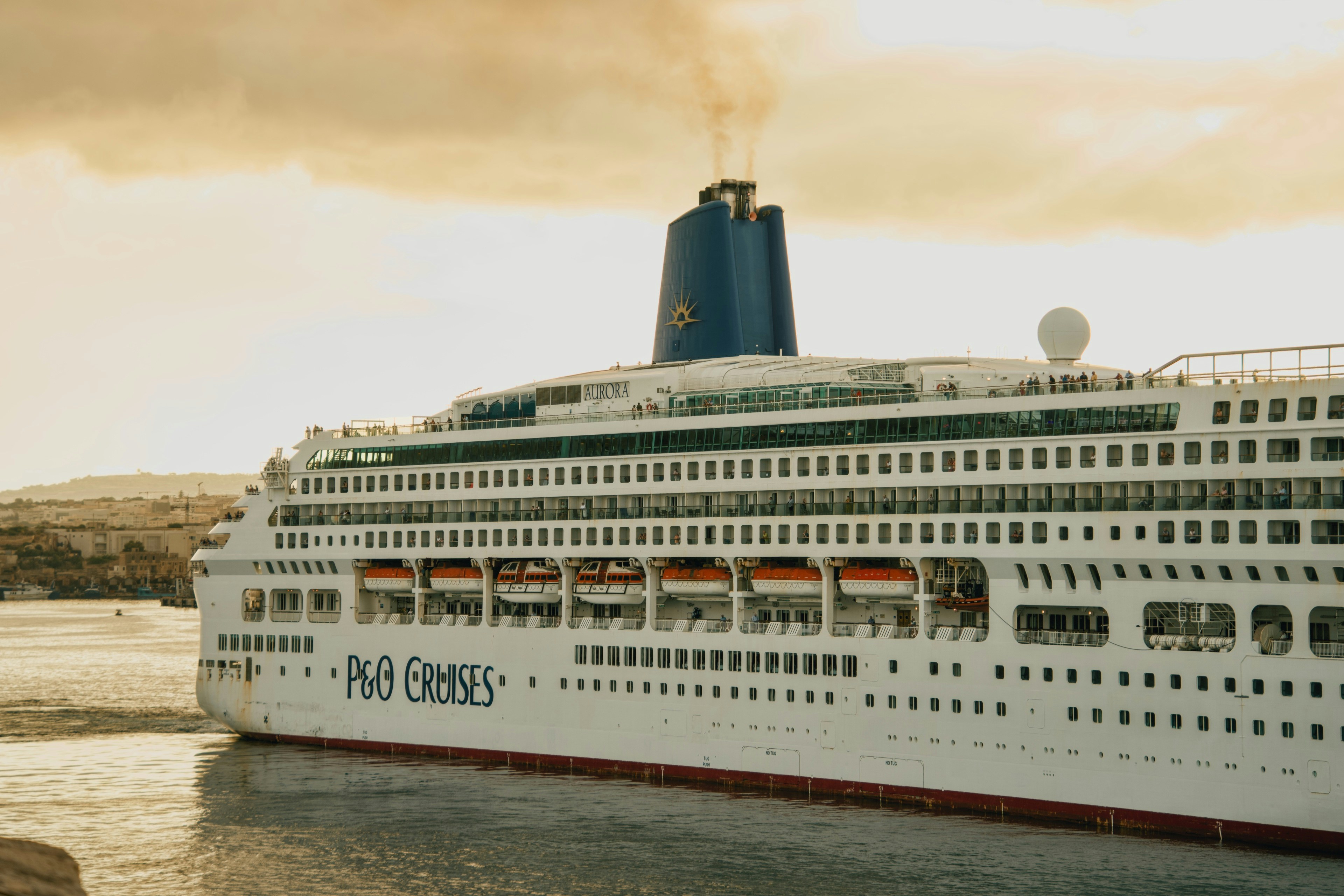 A large P&O Cruises ship named Aurora sailing on water during the golden hour