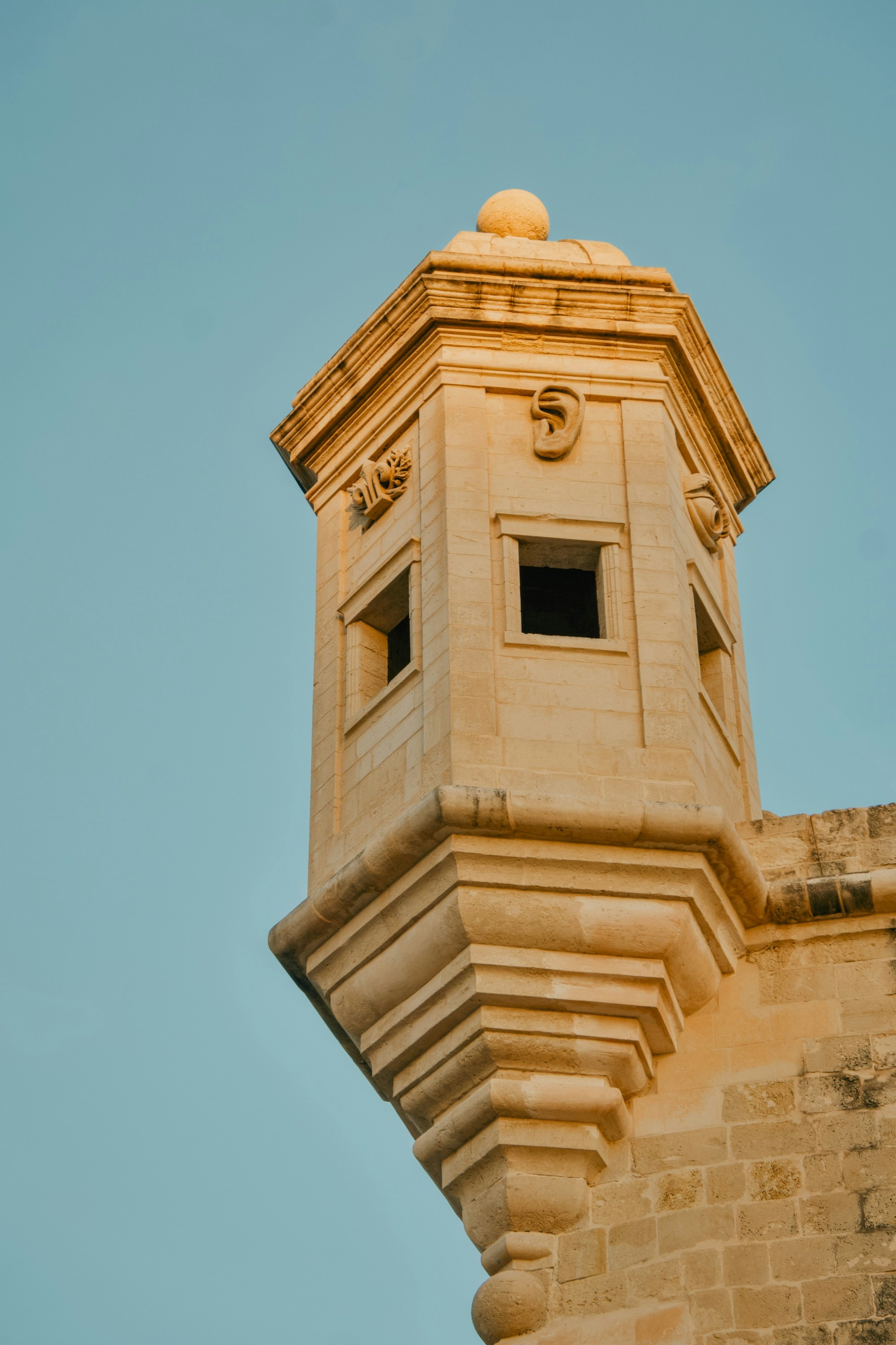 A stone watchtower with carved details against a clear blue sky