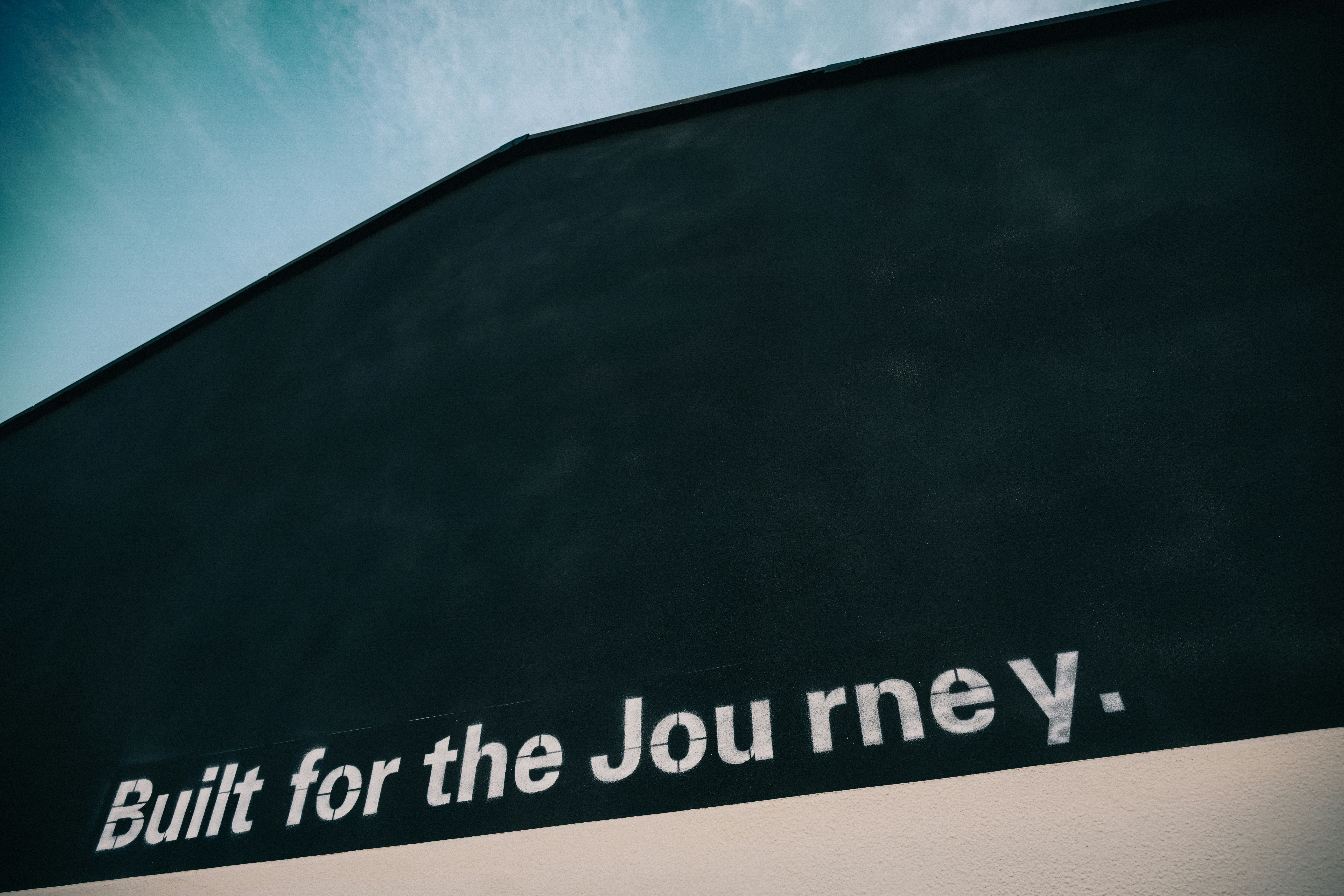 A black wall with white text reading "Built for the Journey" against a blue sky