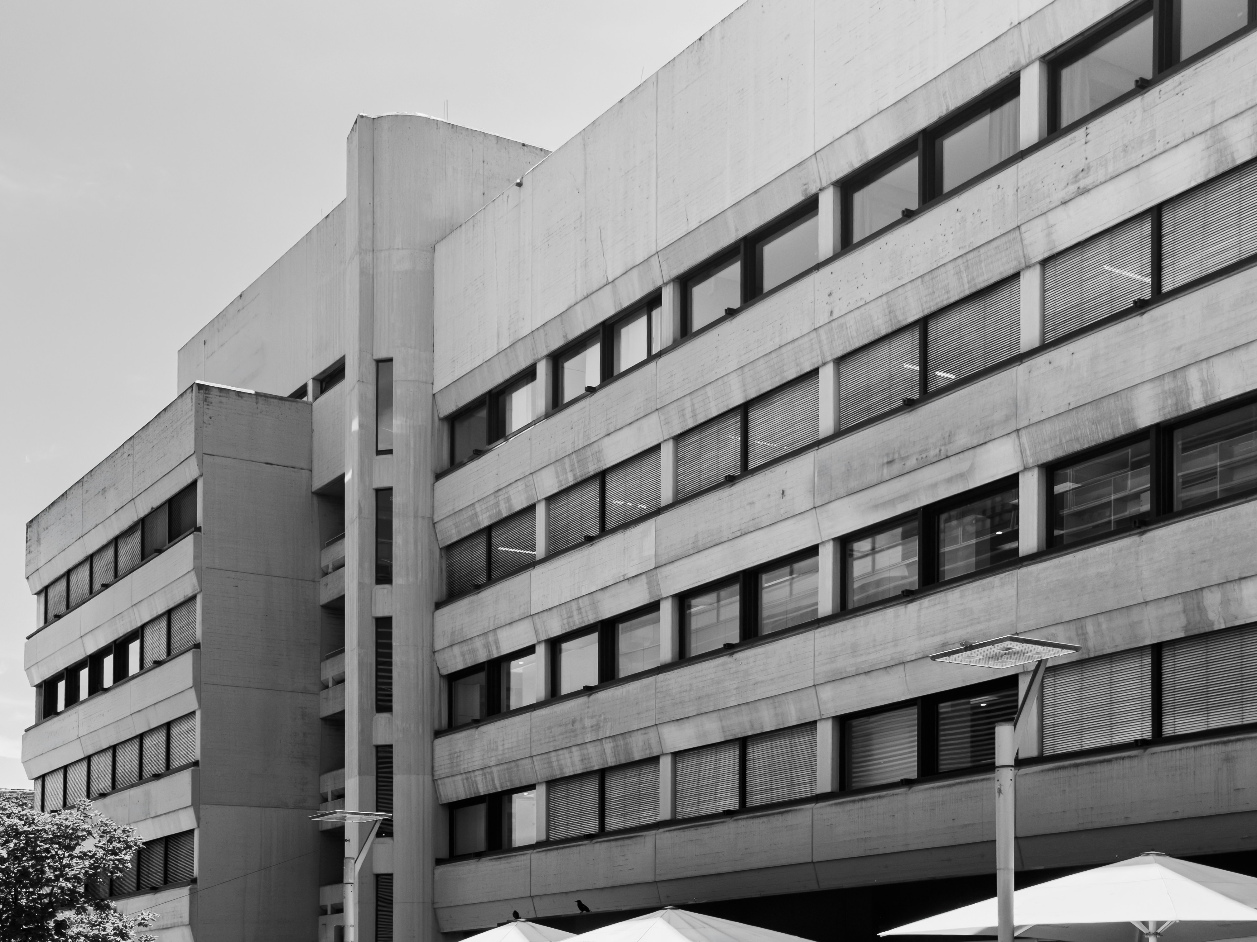 Ein brutalistisches Bürogebäude aus Beton mit Fensterreihen und Außenschirmen