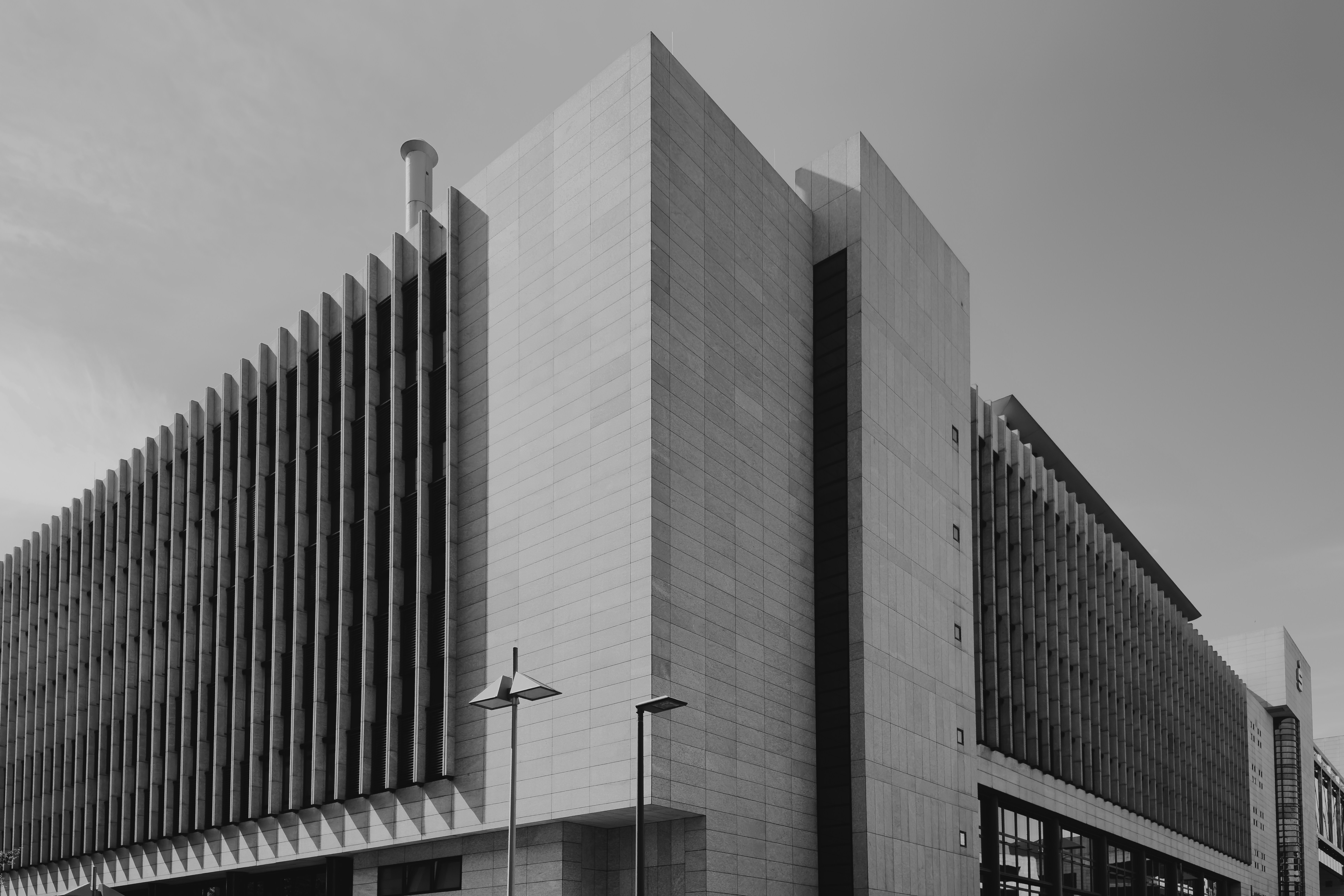 Ein modernes Steingebäude mit senkrechten Fensterfischen und zwei Straßenlaternen