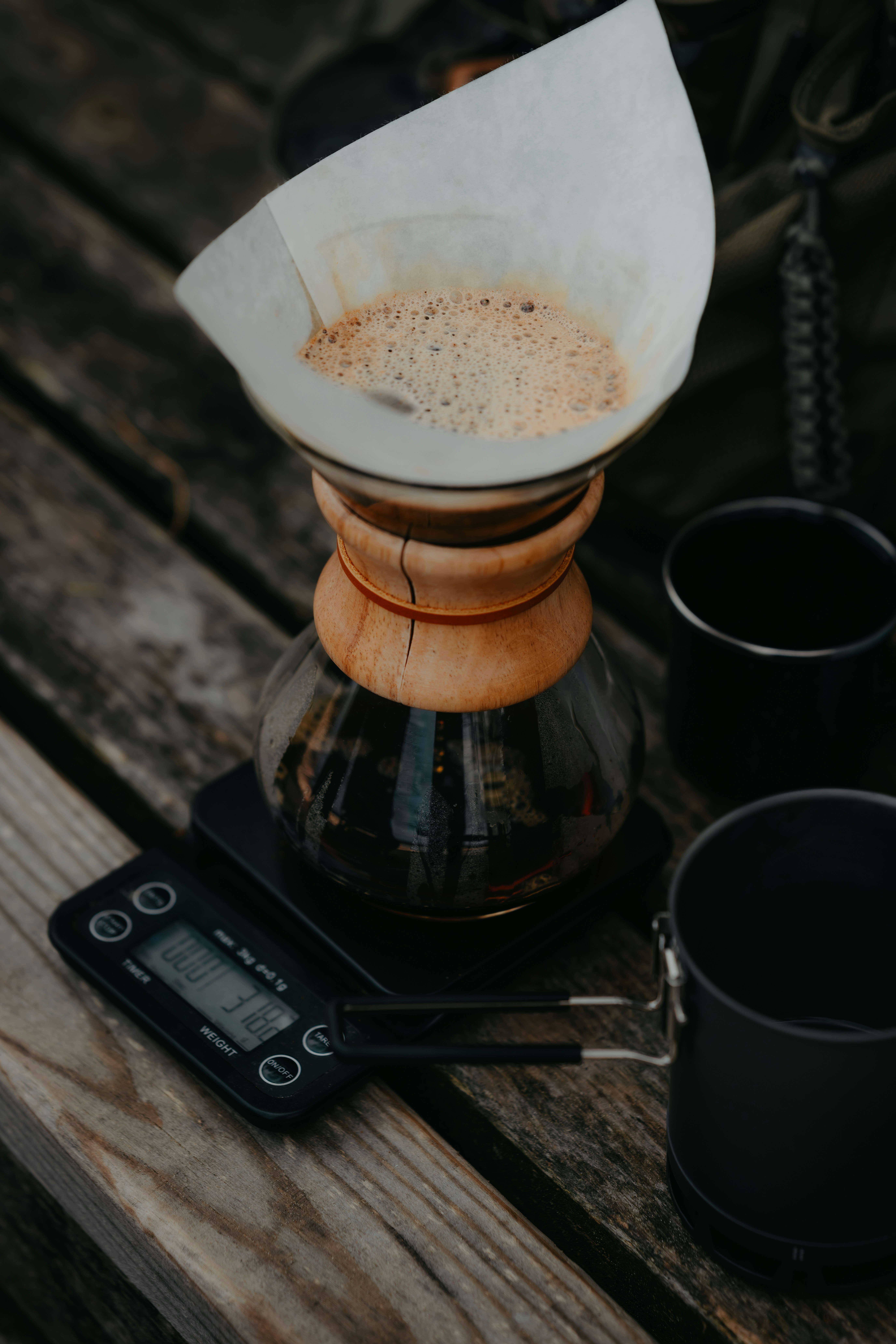 A glass pour-over coffee maker on a digital scale on a wooden surface