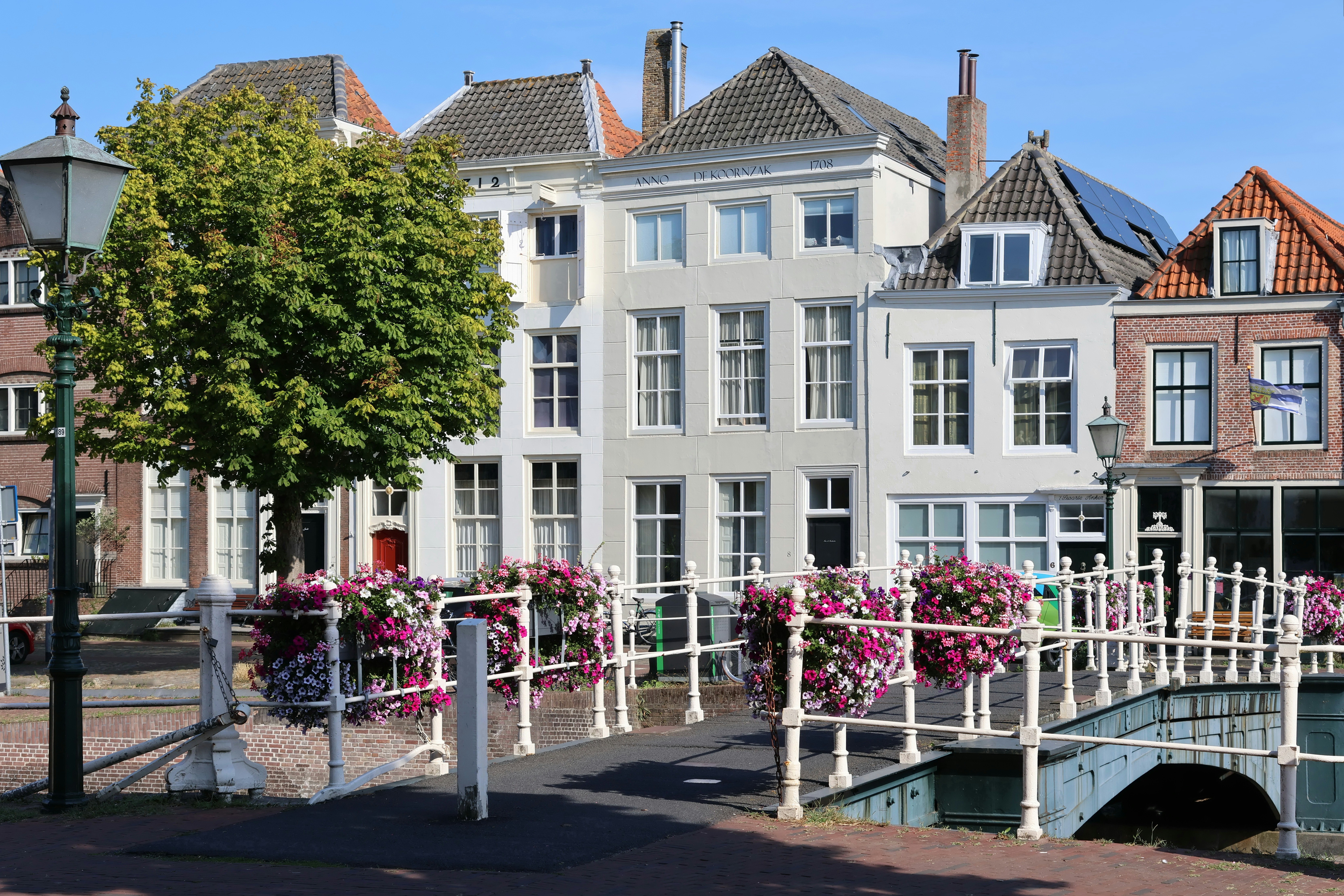 A bridge with flower baskets over a canal in front of historic Dutch houses