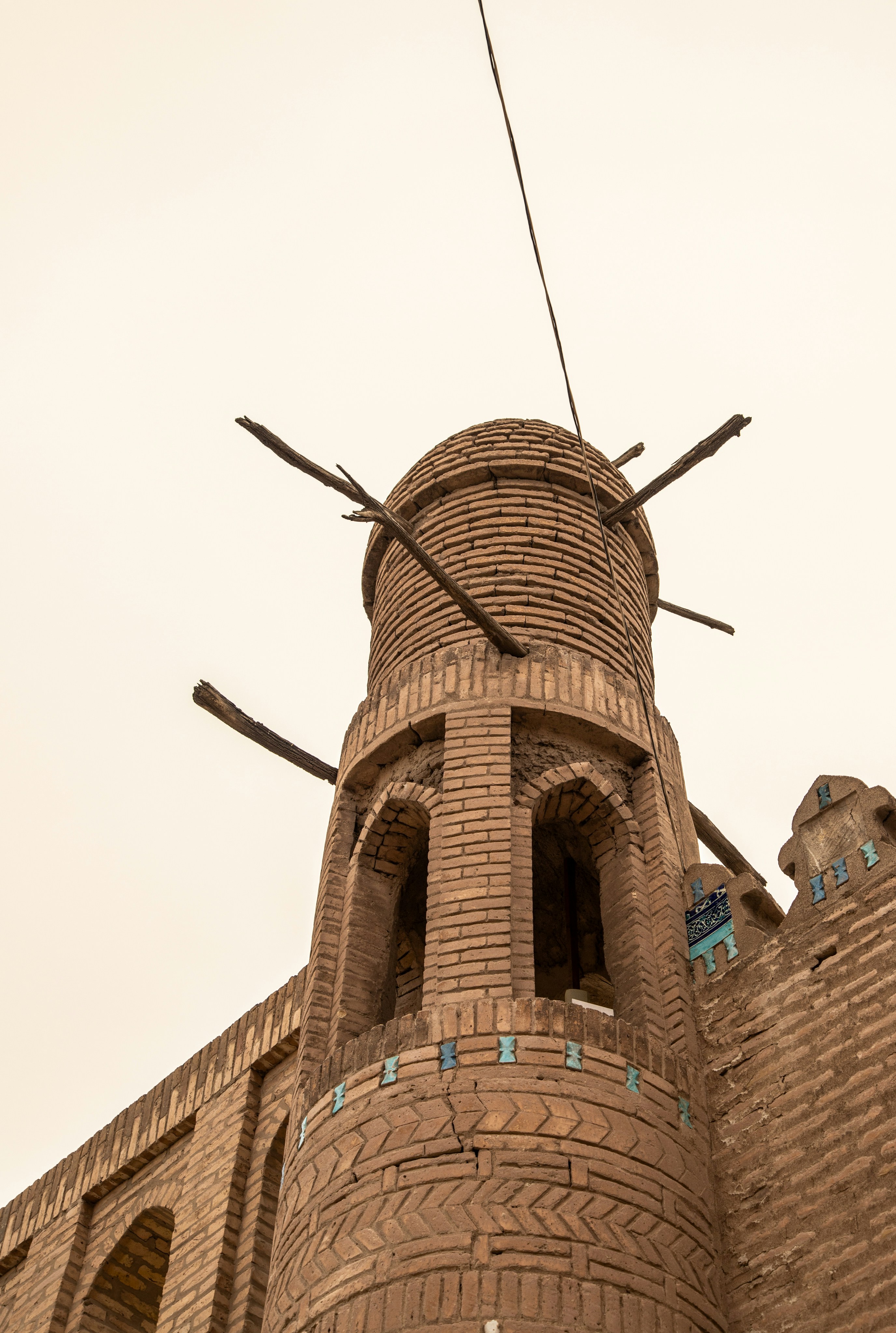 Uma torre cilíndrica de tijolos com vigas de madeira que se projetam de um edifício antigo