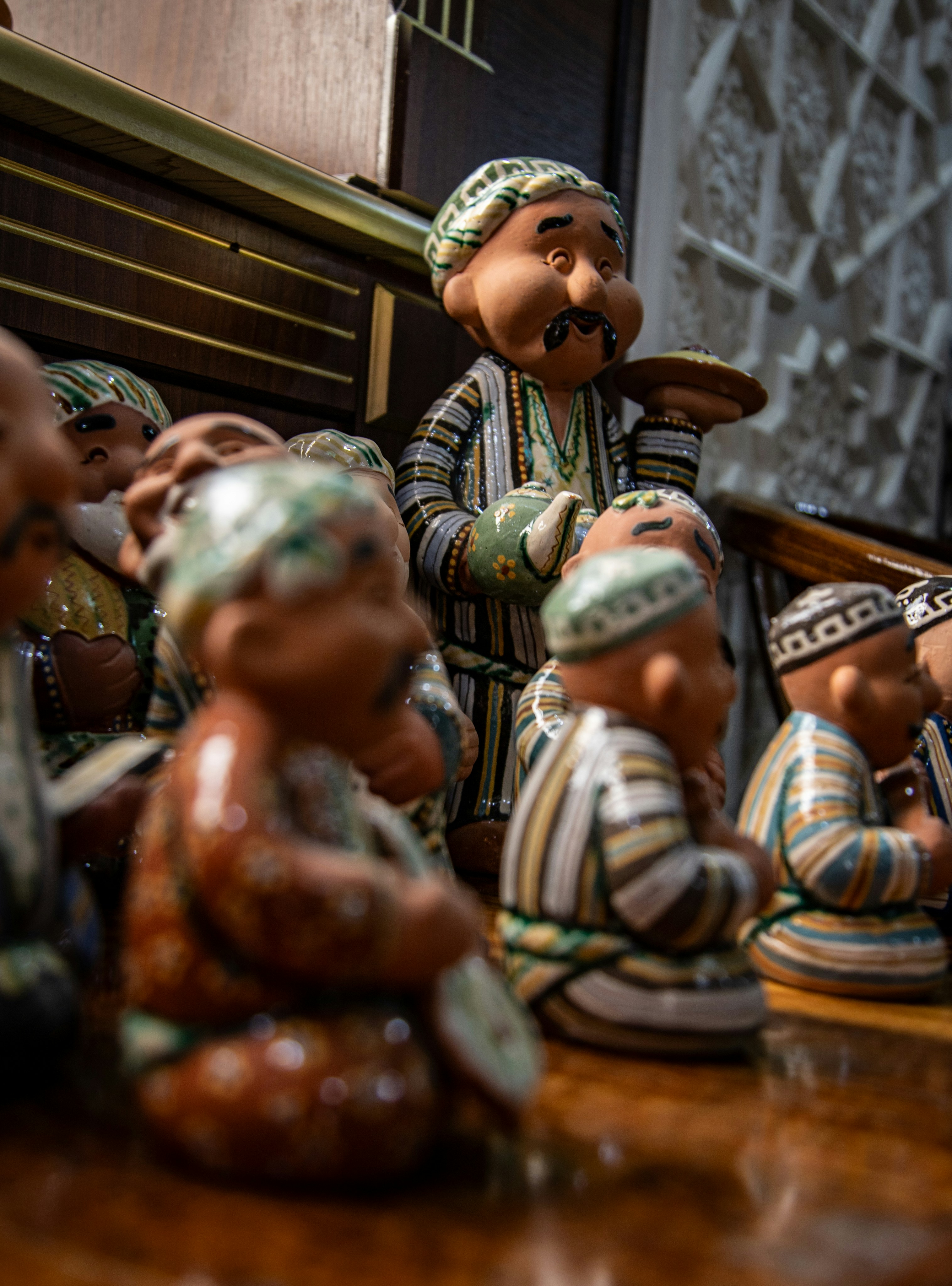 Um grupo de pequenas estatuetas de cerâmica vestindo vestes tradicionais listradas e toucas sobre uma mesa