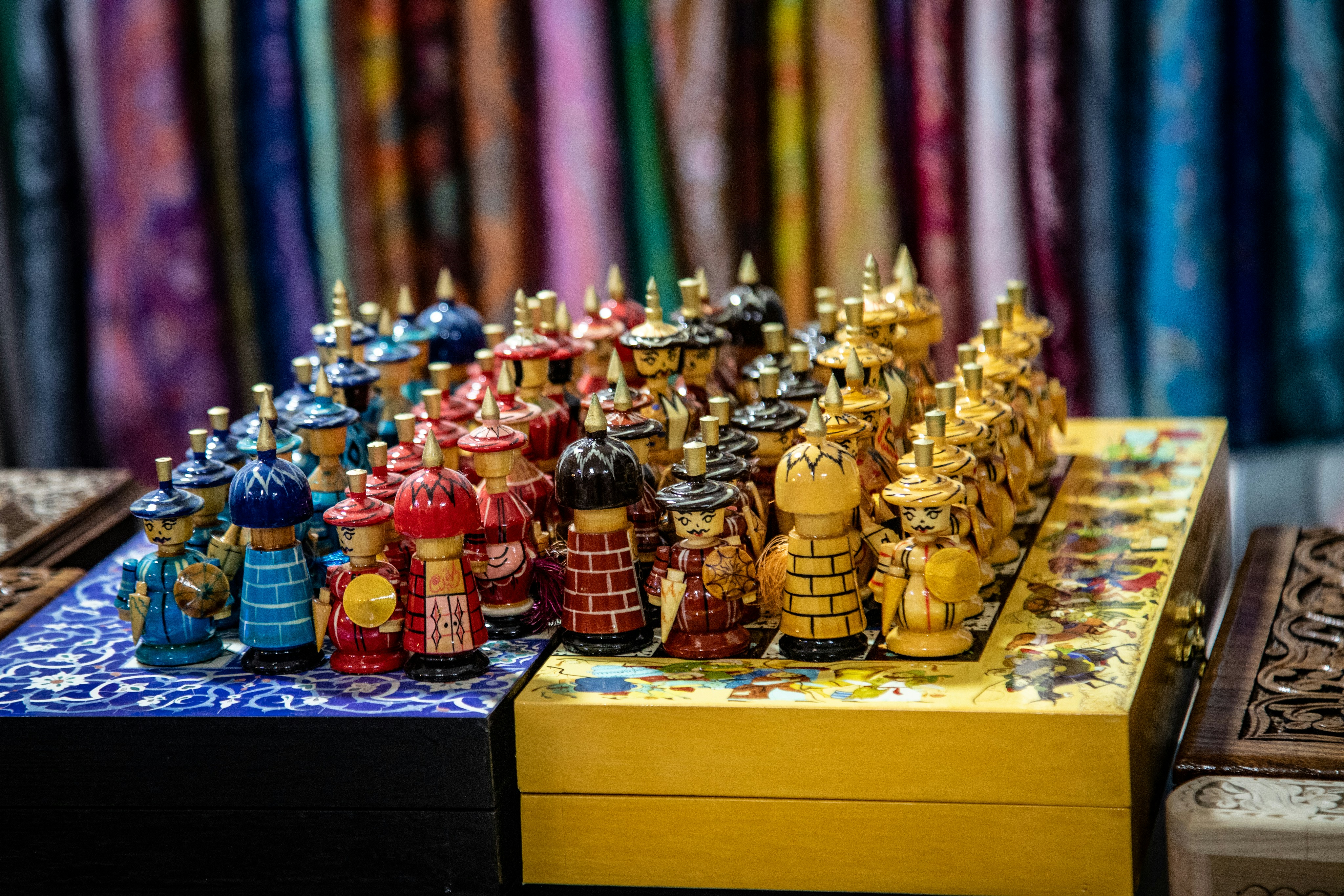Peças de xadrez de madeira feitas à mão, com trajes tradicionais, em um tabuleiro colorido