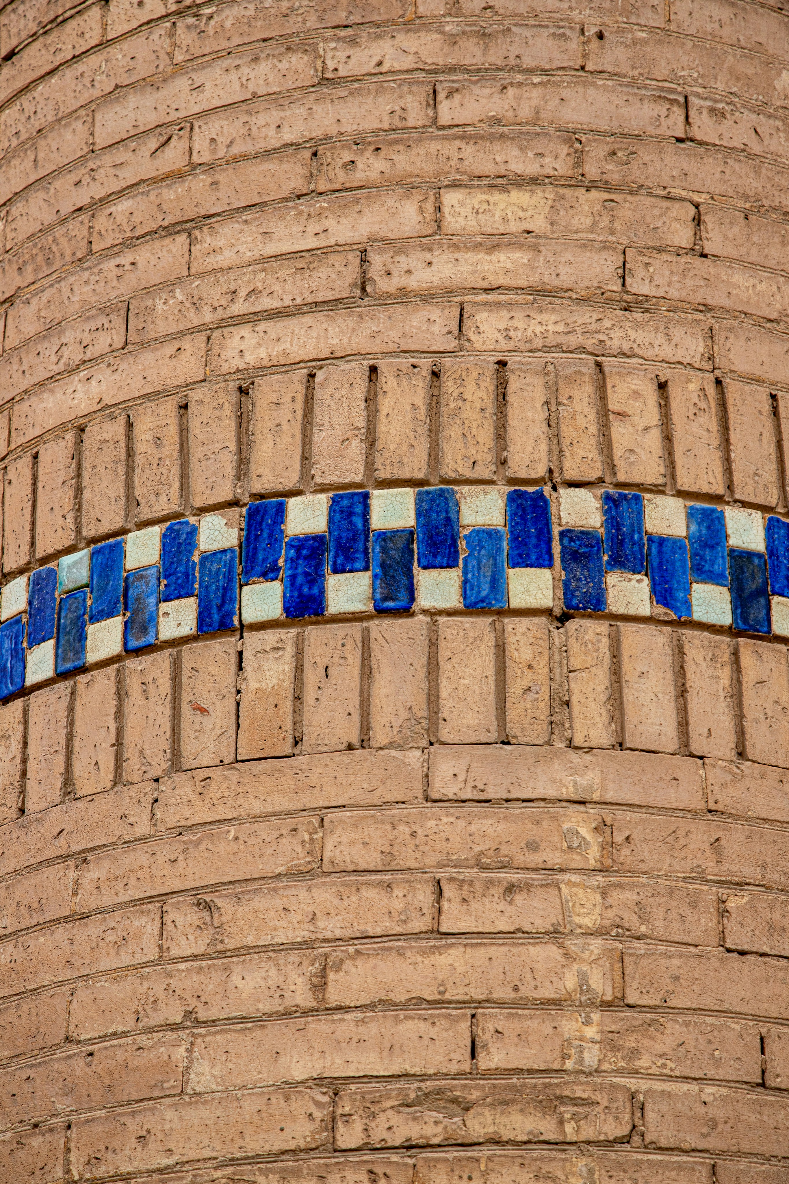 Uma parede curva de tijolos com uma faixa decorativa de azulejos azuis e brancos