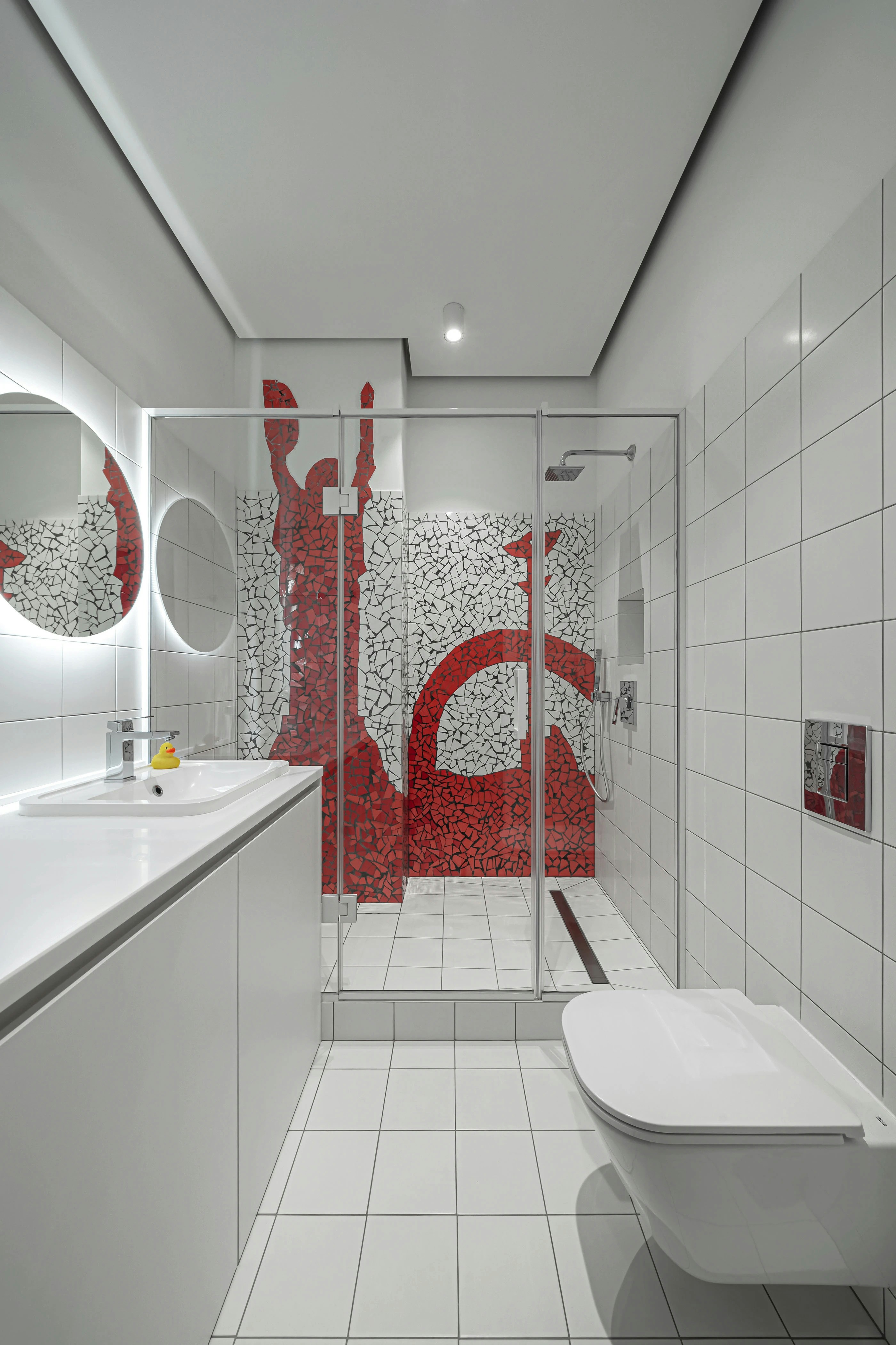 A modern bathroom with white tiles and a shower featuring red mosaic art