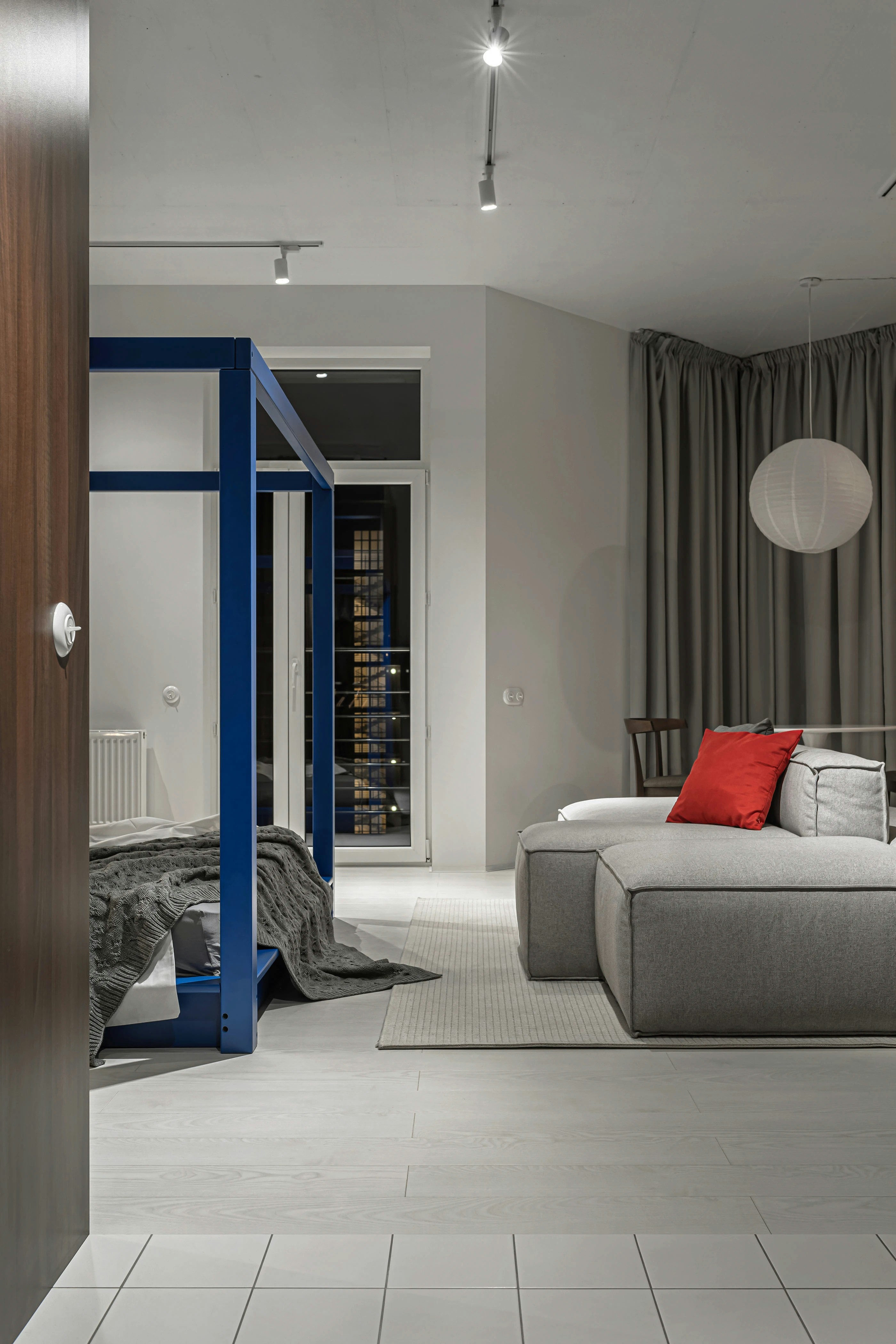 A blue canopy bed and a grey sectional sofa in a modern bedroom