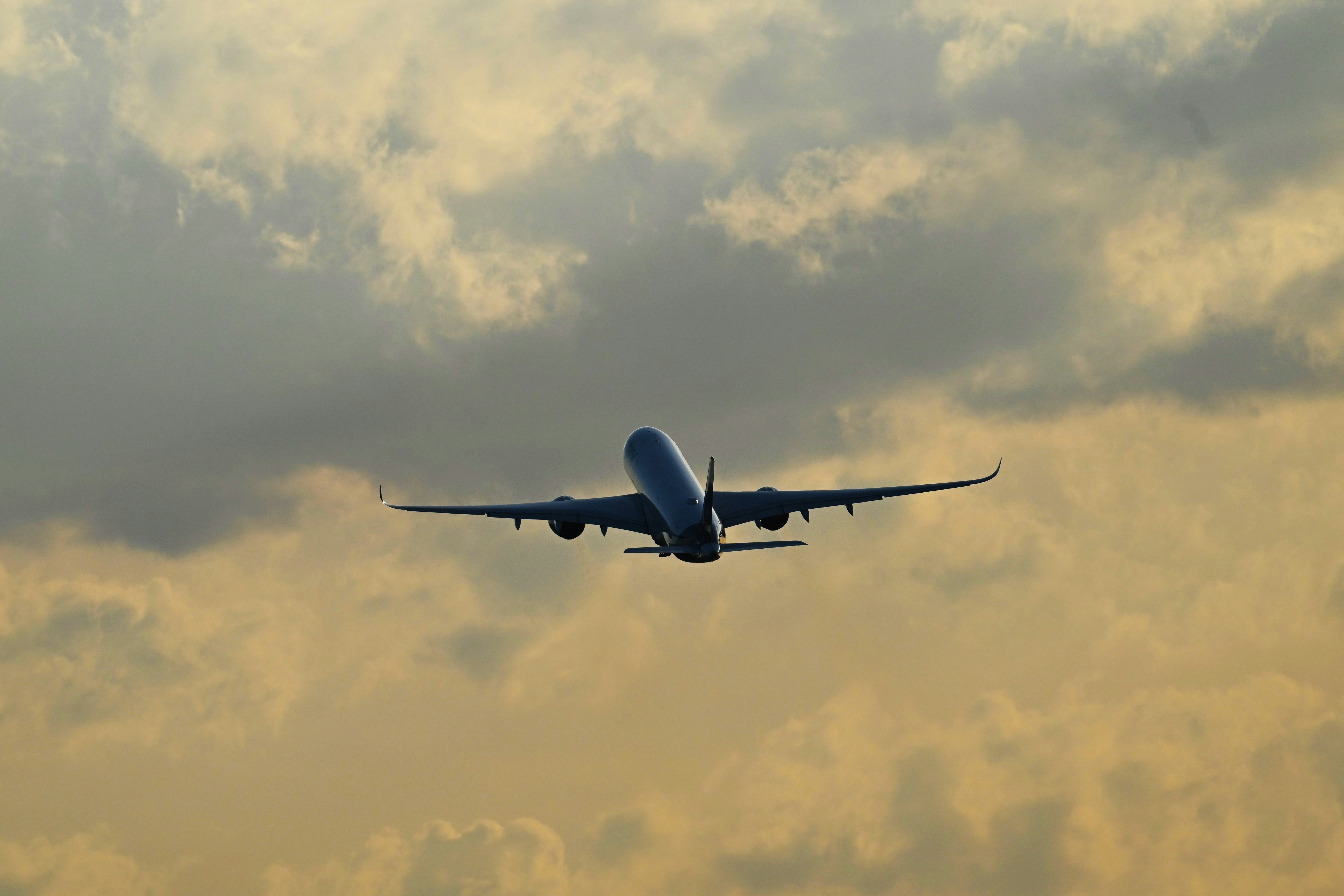 A passenger airplane climbing into a cloudy sky during the golden hour