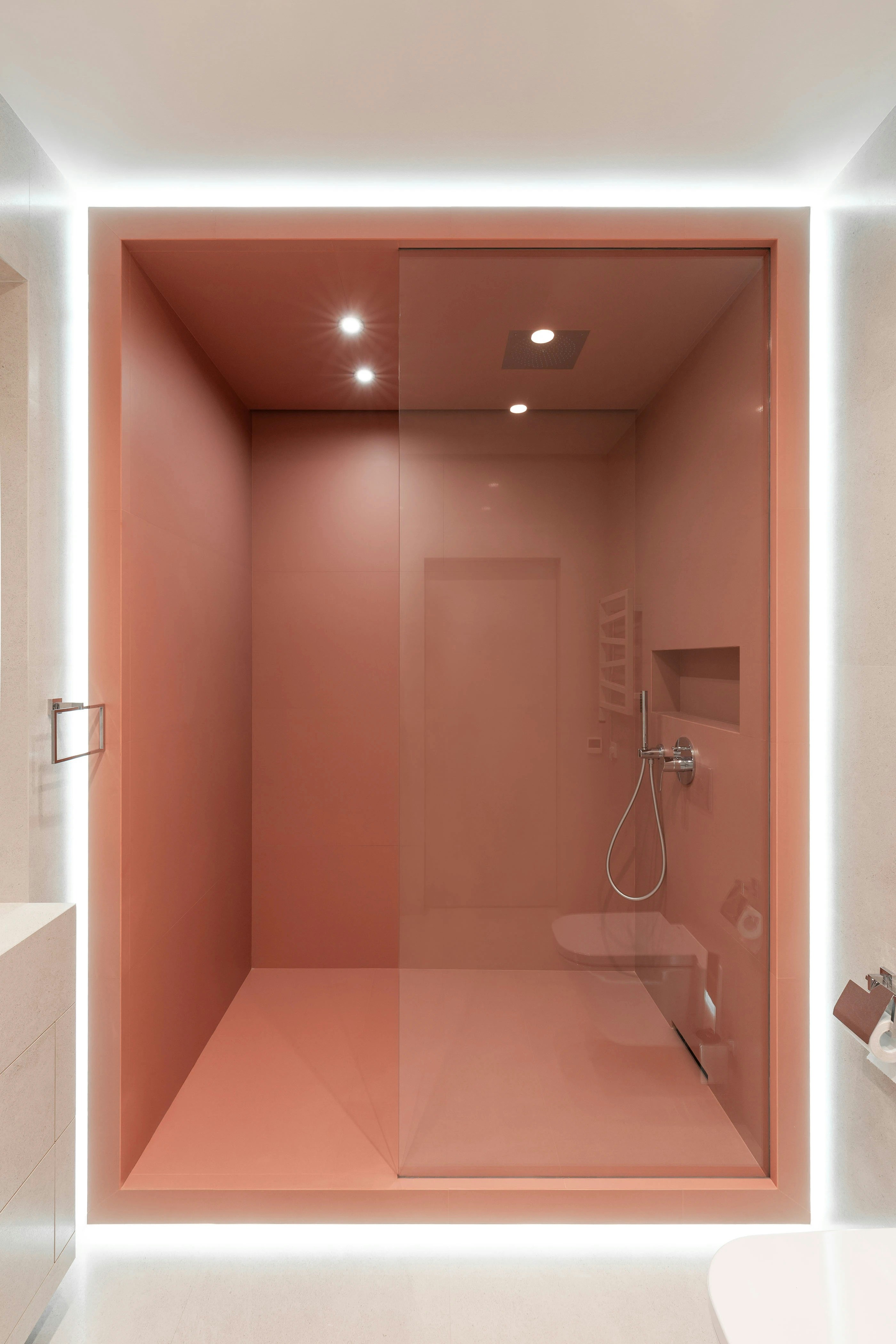 A walk-in shower with matte pink walls and a glass door in a bathroom