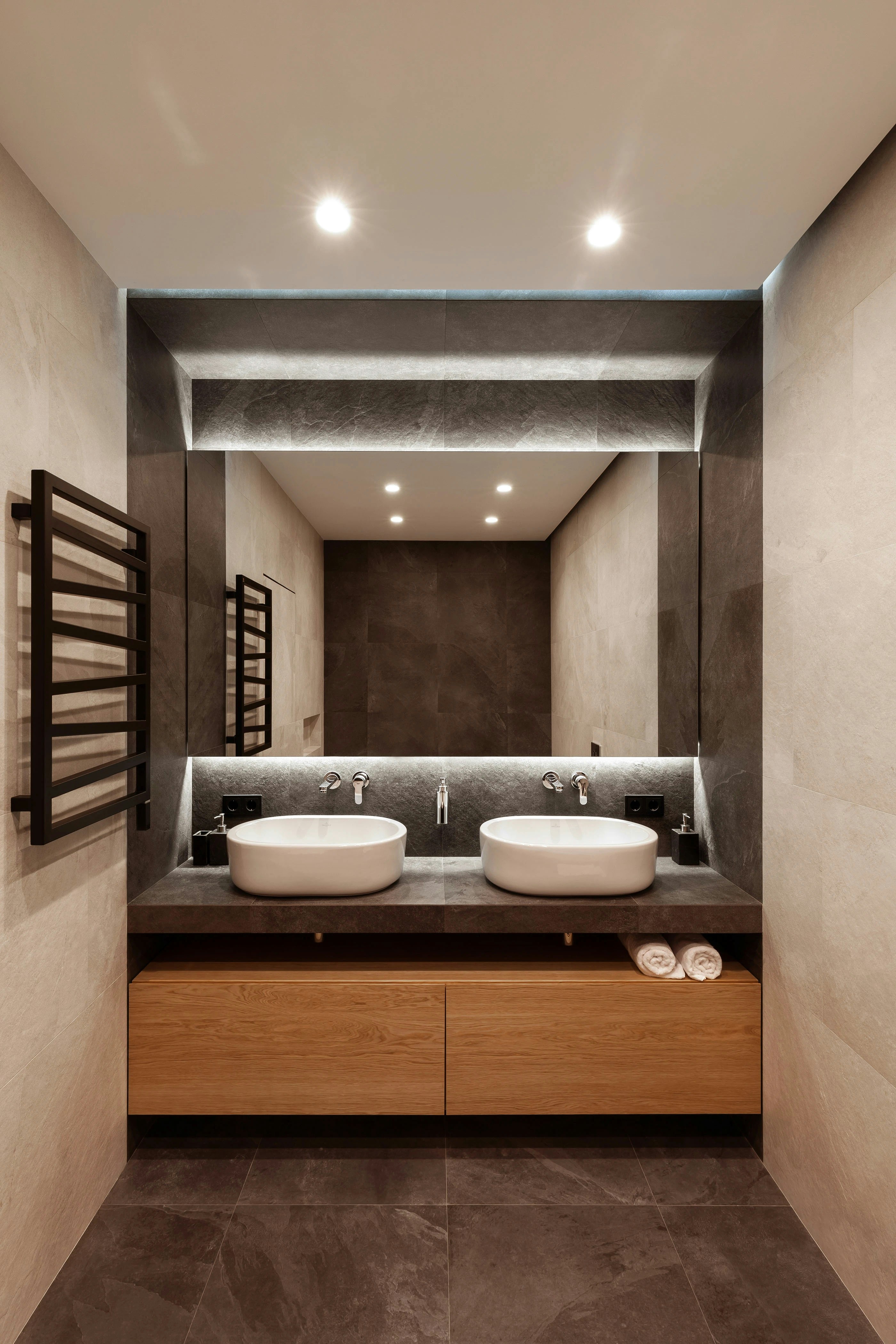 A modern bathroom with two white vessel sinks on a dark stone vanity