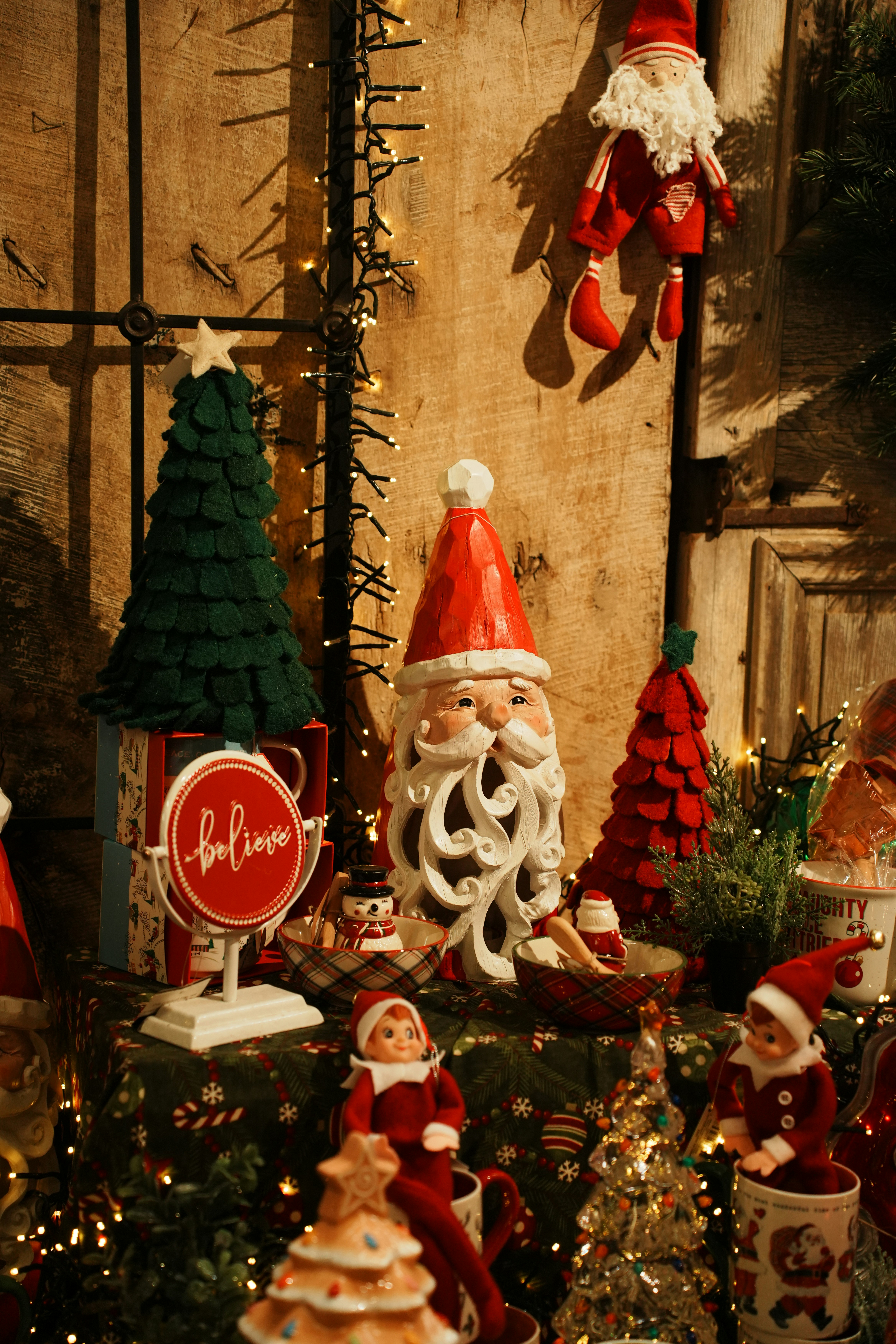 Christmas decorations including a carved Santa figure, felt trees, and elf dolls on a table