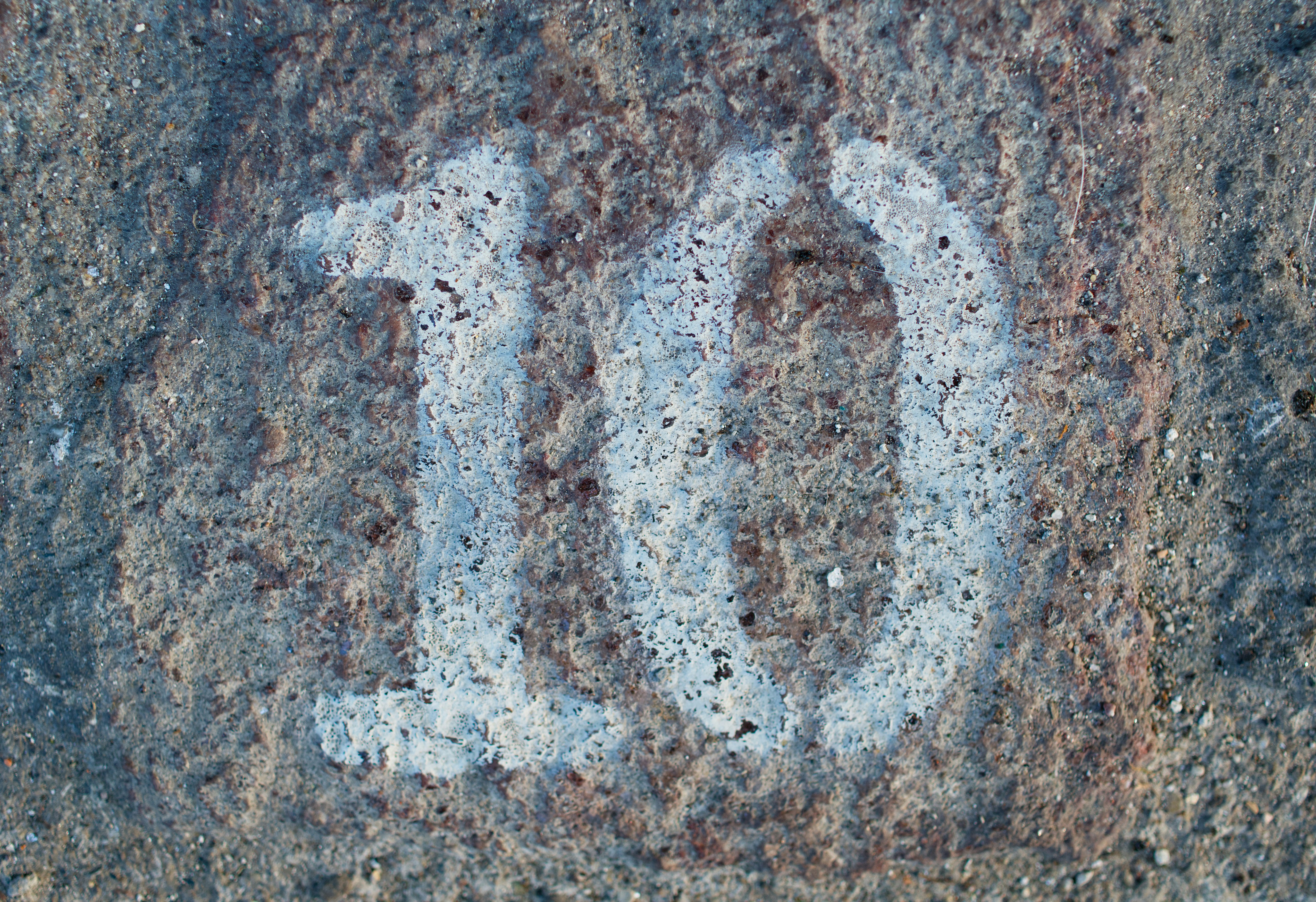The number ten painted in white on a rough grey stone surface