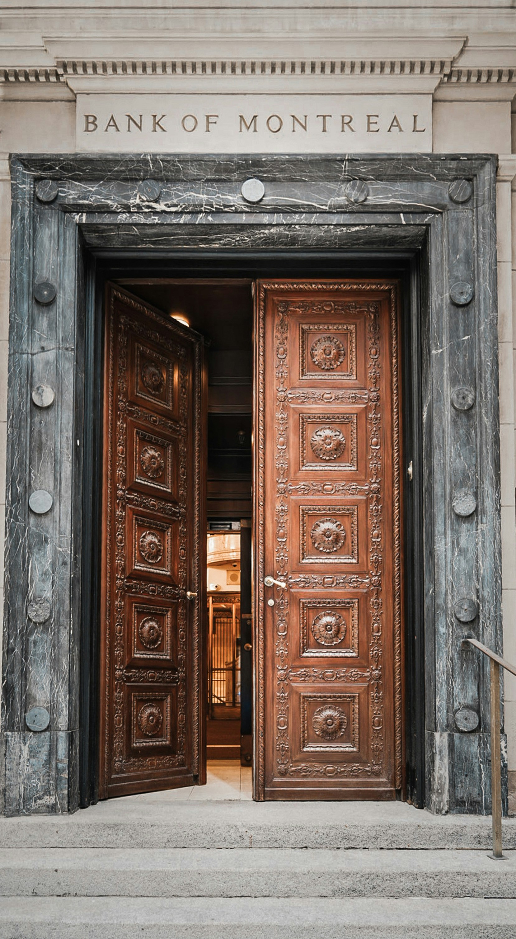 Ornate wooden doors at the Bank of Montreal entrance with dark marble trim