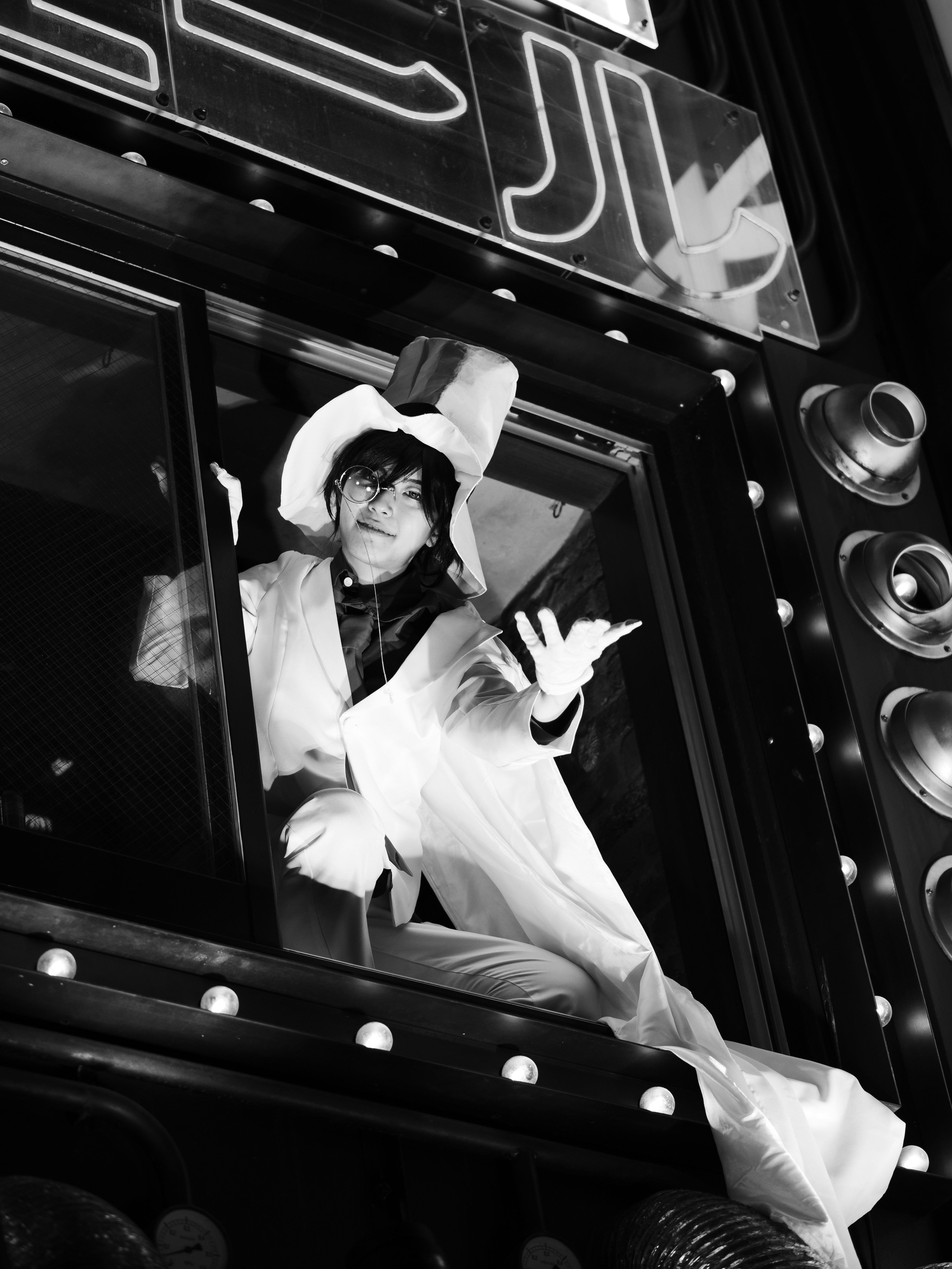 A person in a white top hat and cape leaning out of a window