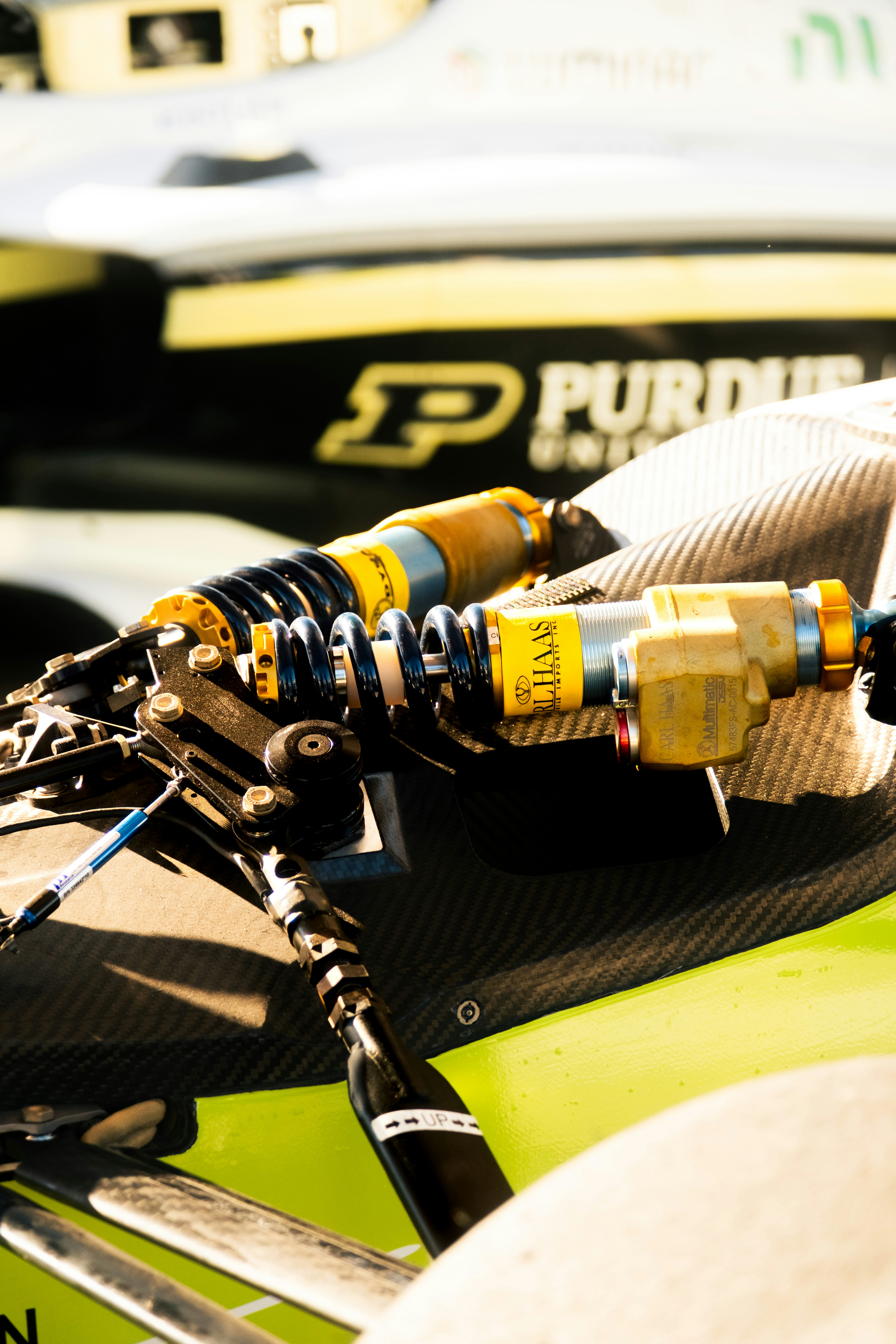 Close-up of carbon fiber suspension components on a bright yellow race car