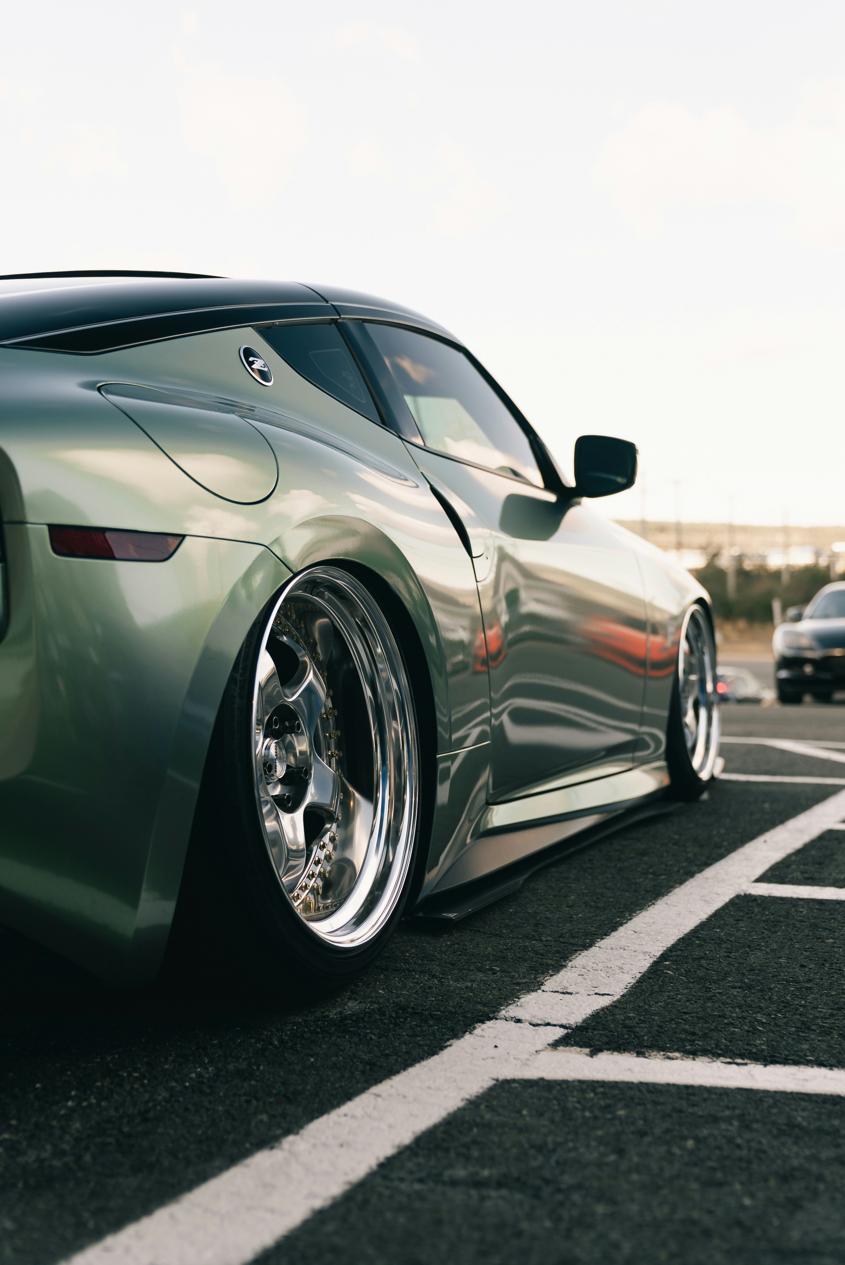A lowered light green sports car with chrome wheels parked in a lot