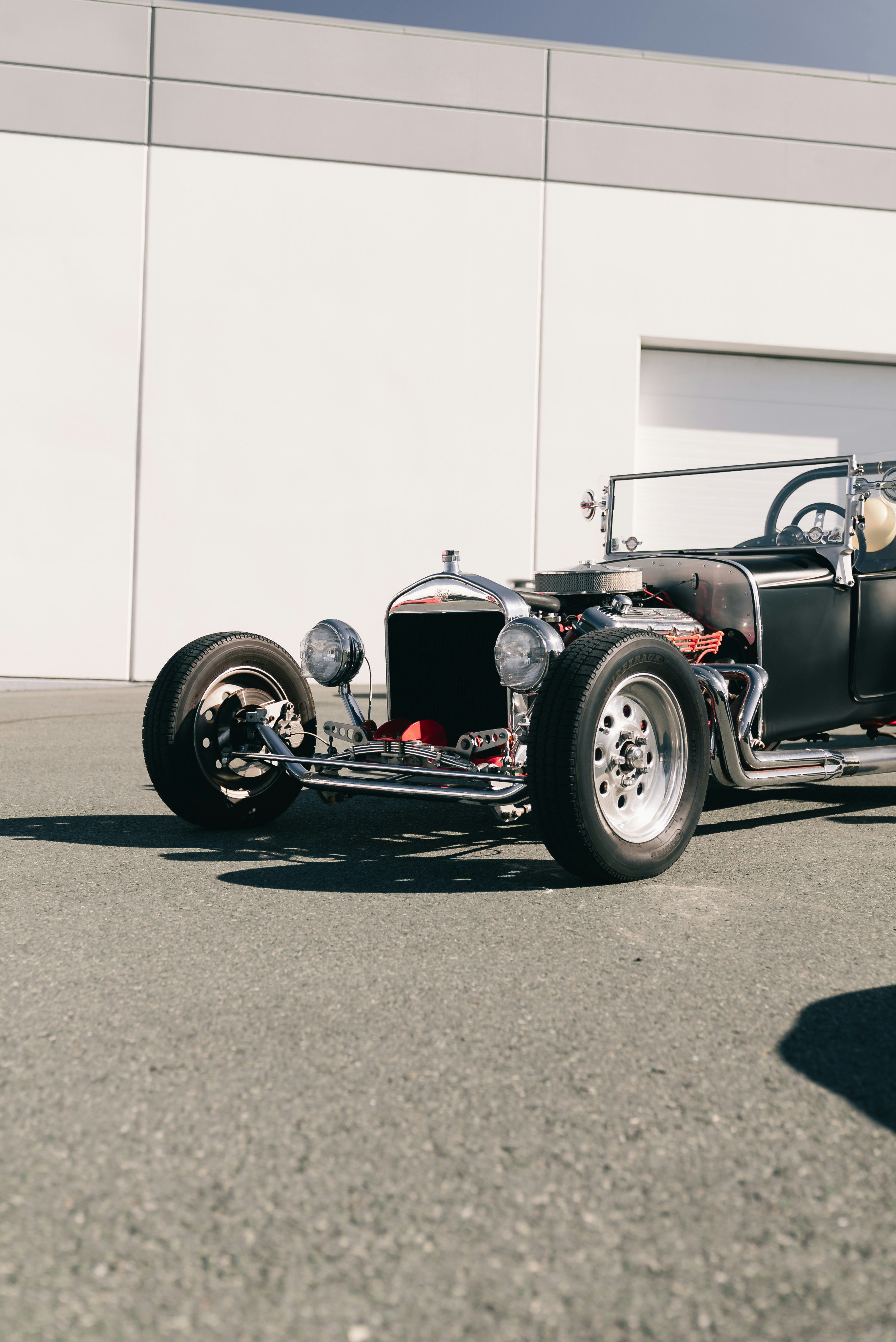A black hot rod with chrome engine parts parked on asphalt