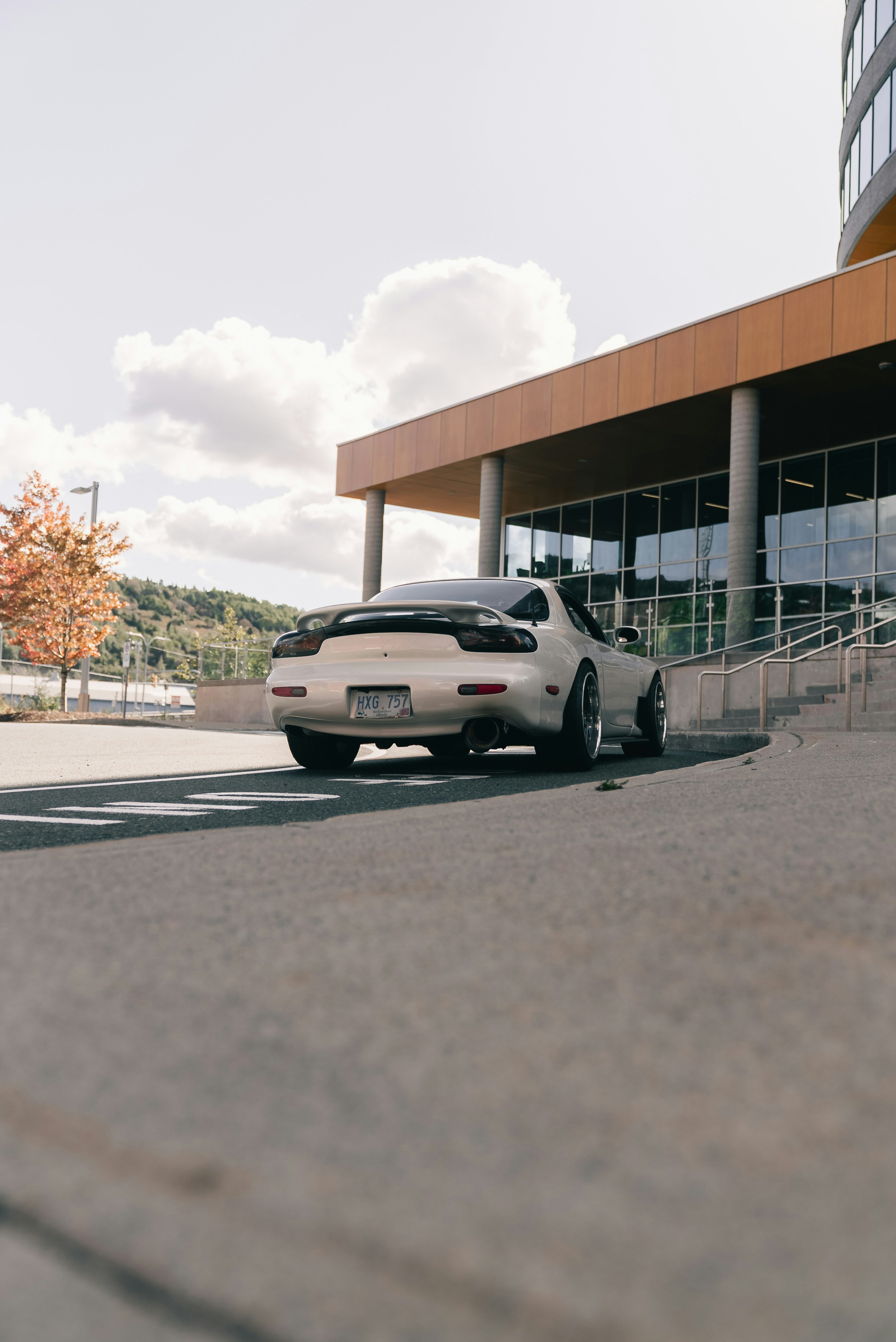 Un coche deportivo blanco aparcado en una entrada pavimentada cerca de un edificio moderno