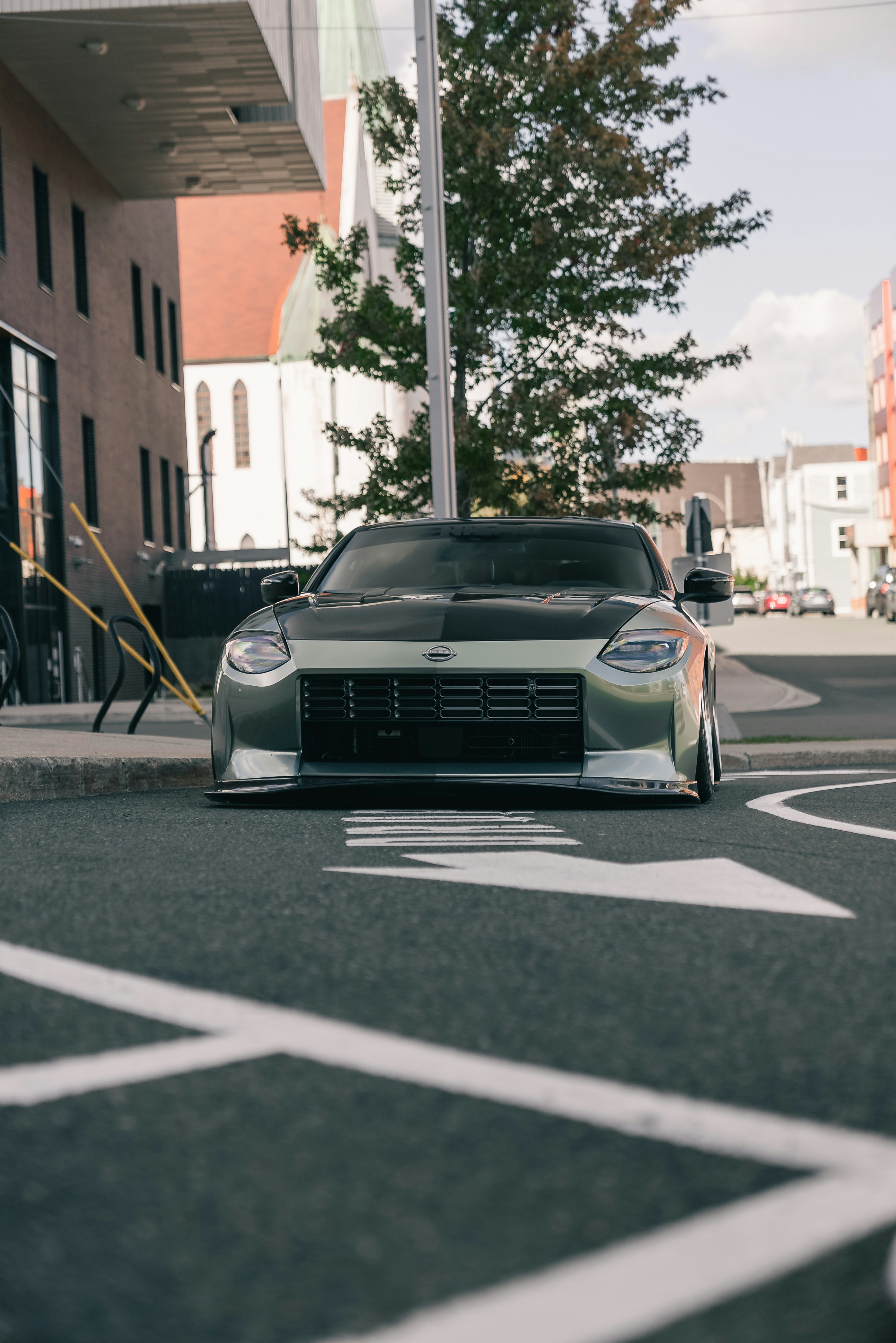 Un Nissan Z deportivo verde aparcado en una calle asfaltada cerca de un edificio