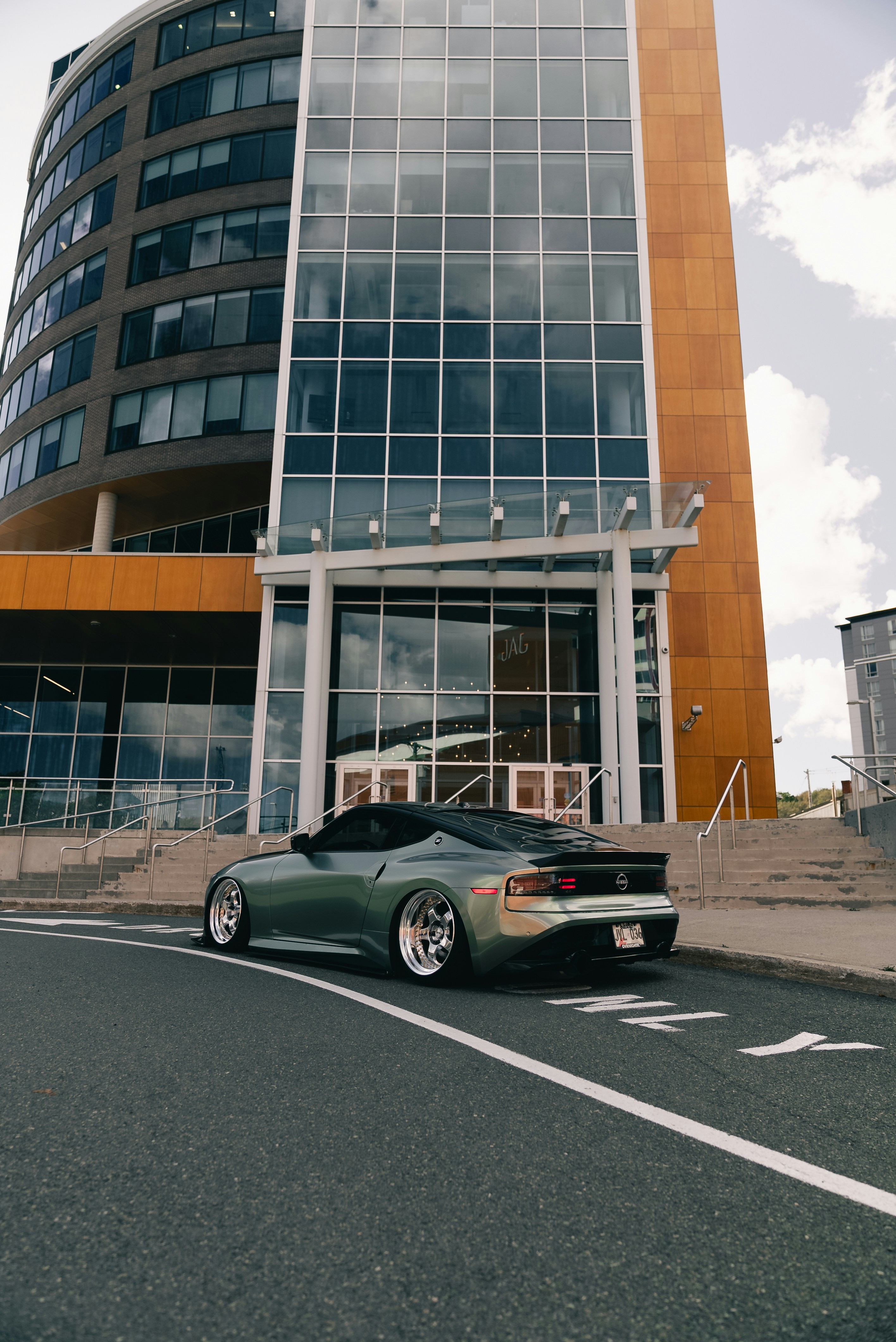 Un Nissan Z deportivo verde modificado aparcado en una calle asfaltada junto a un edificio