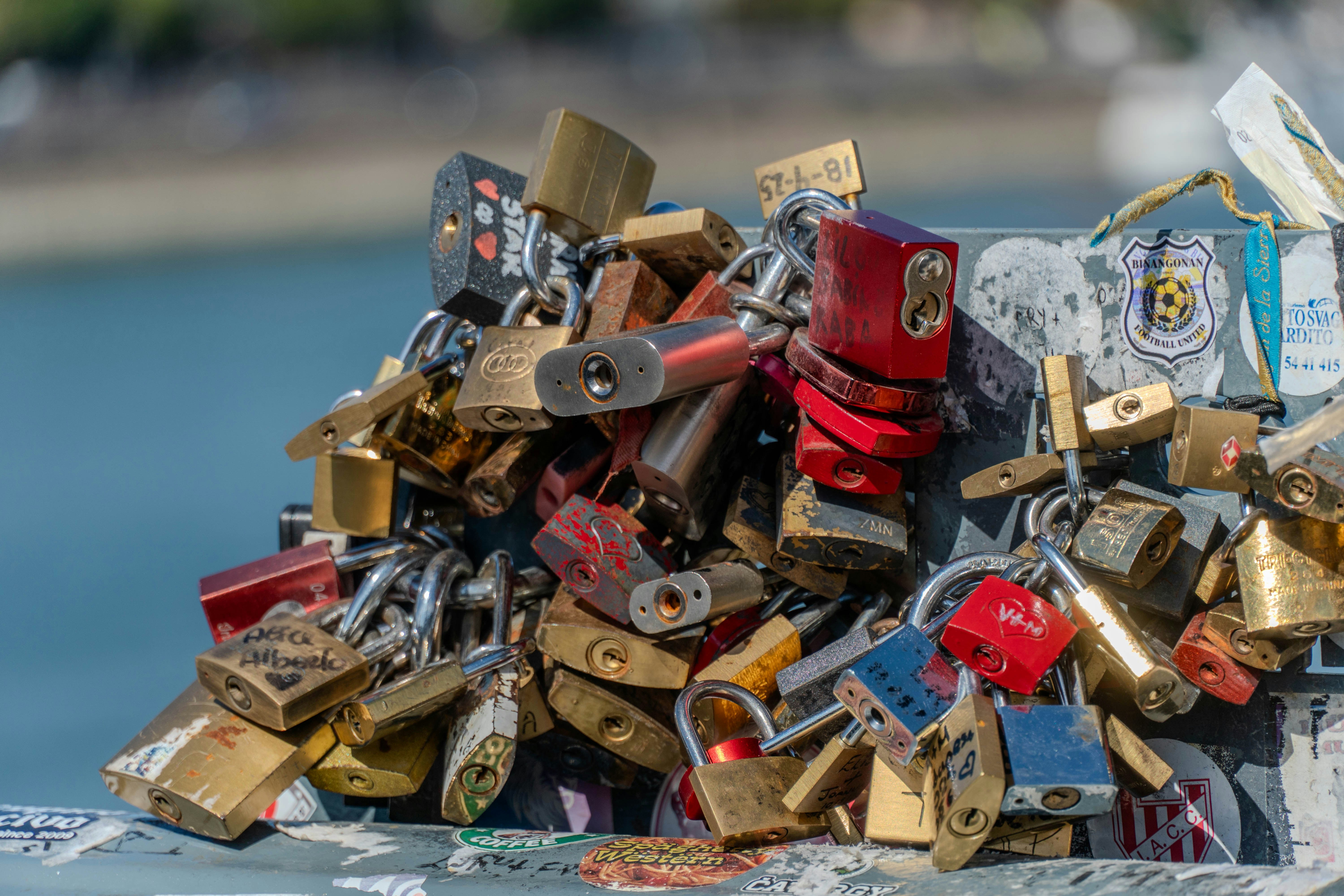 A cluster of metal padlocks attached to a railing with stickers