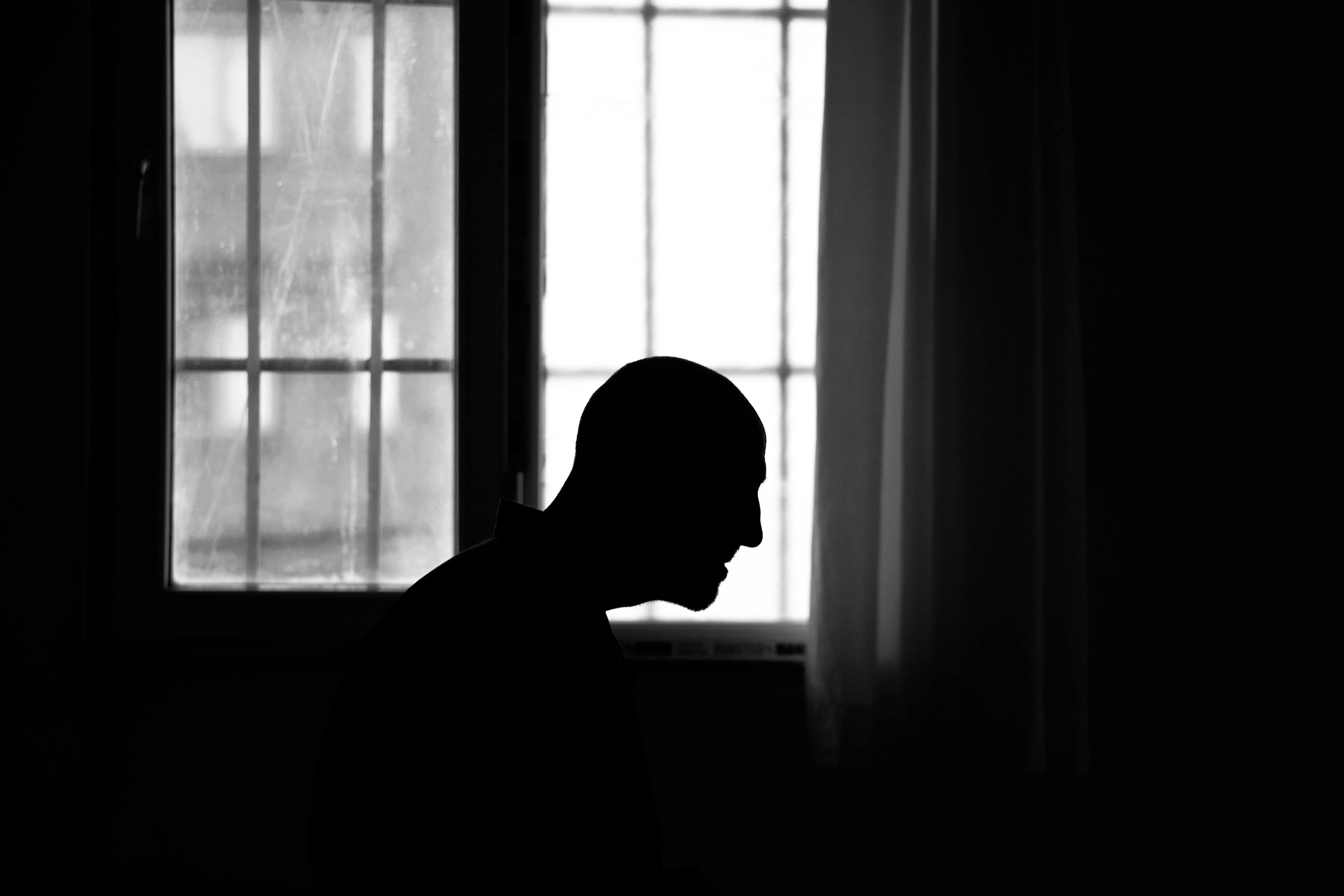 A silhouette of a person against a bright window with a grid frame