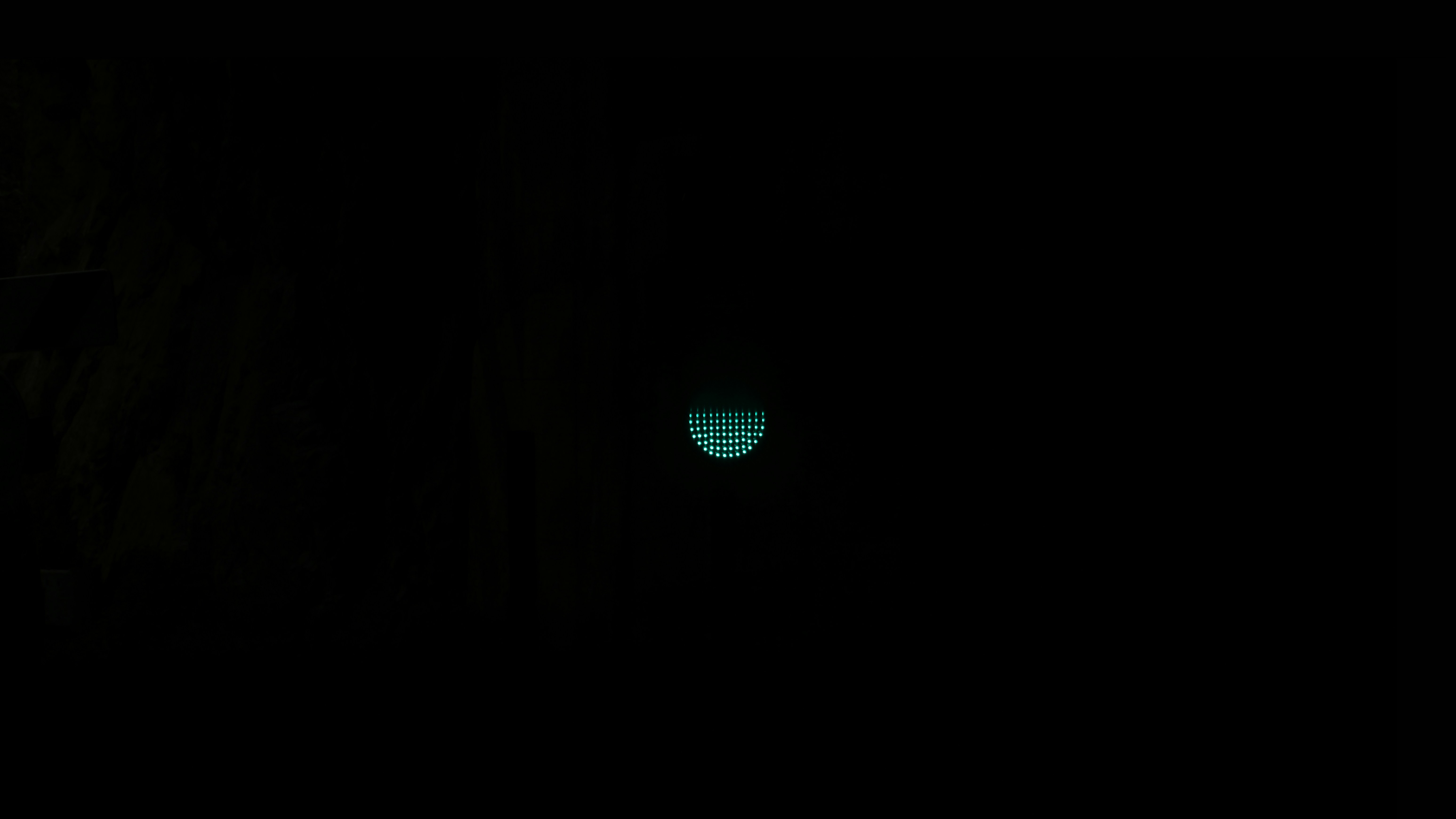 A small glowing circle of green dots centered in a vast black void