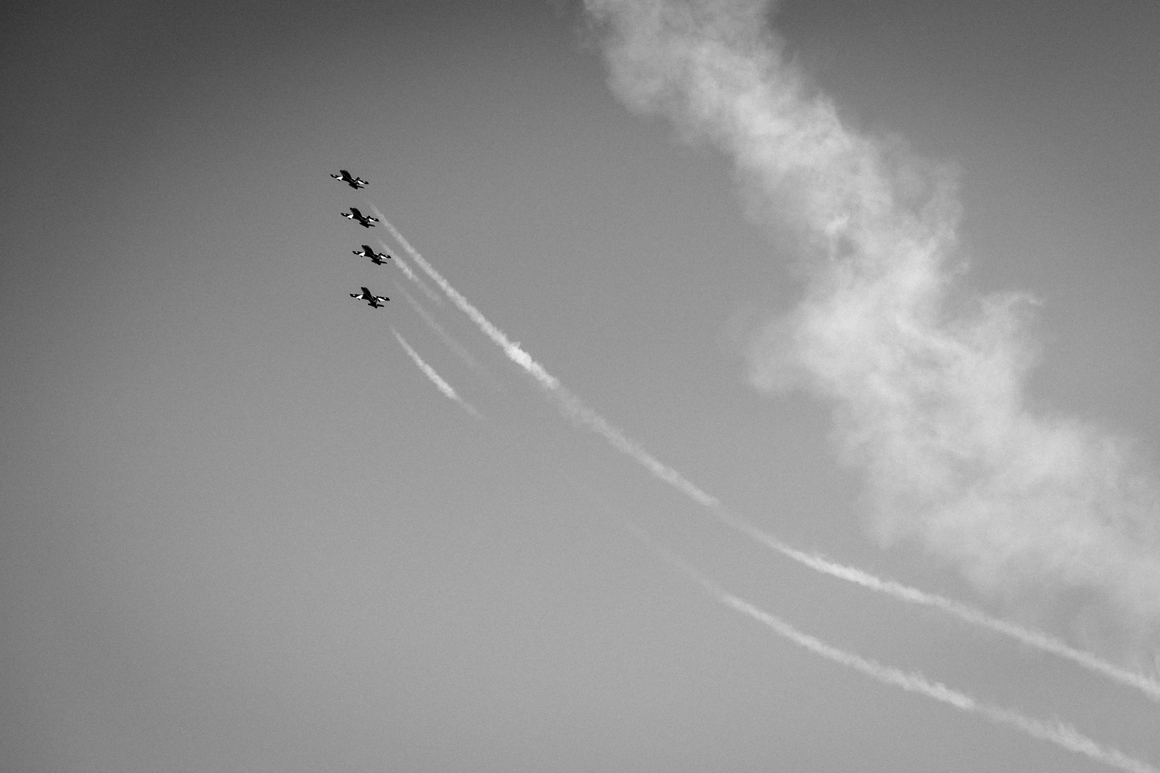 Four airplanes flying in formation leaving long white contrails across a clear sky