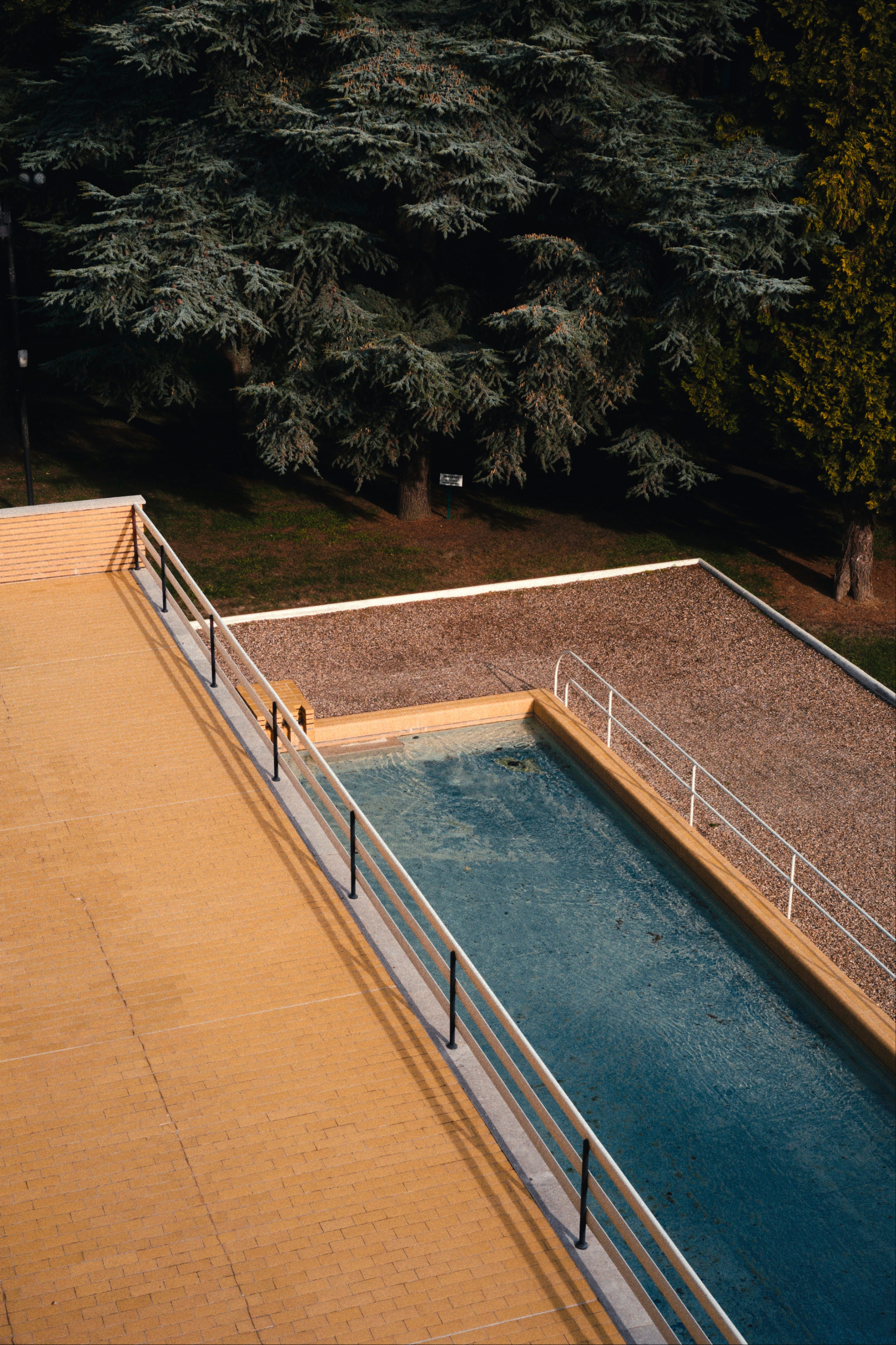 A rectangular swimming pool with blue water beside a yellow tiled patio