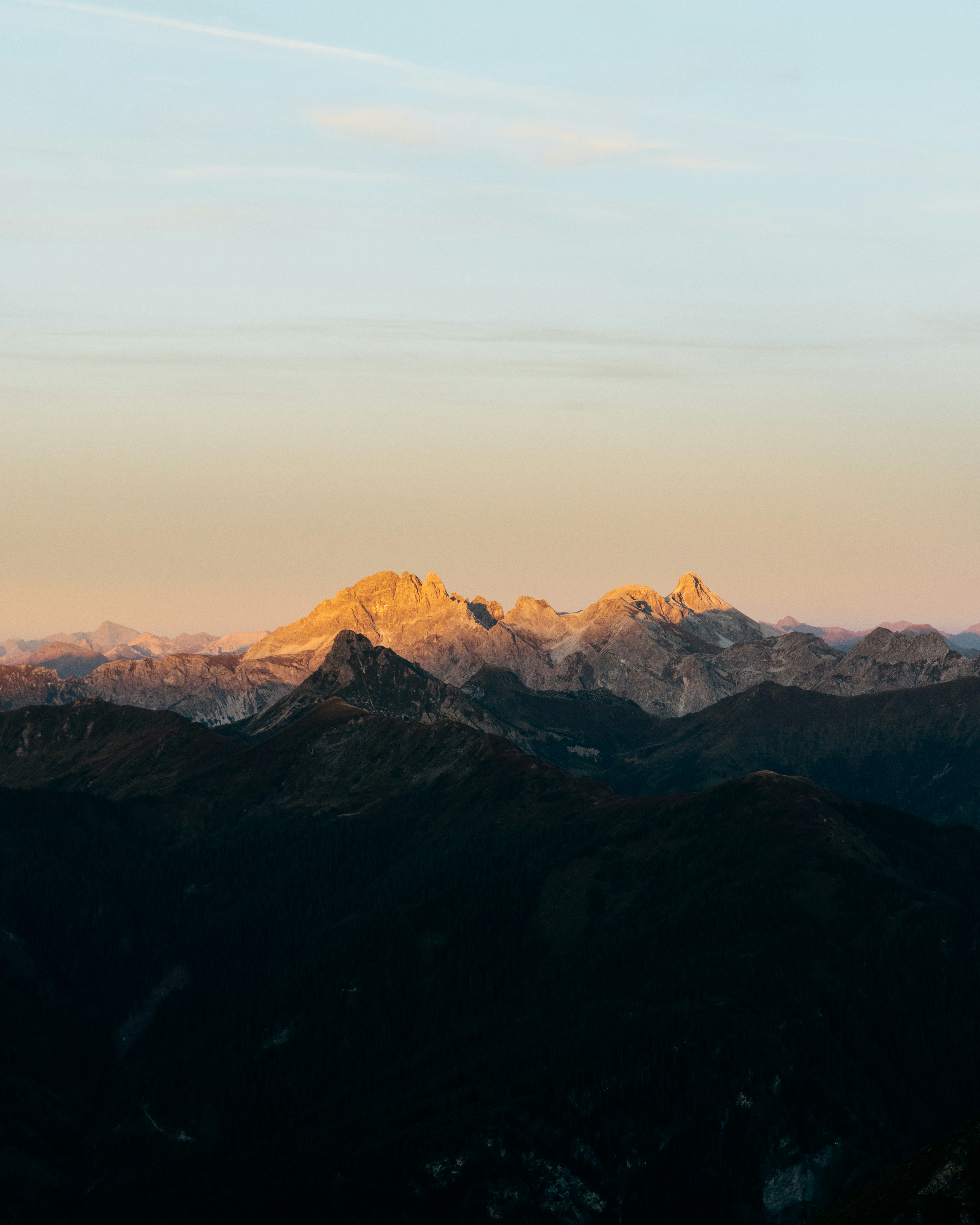 Jagged mountain peaks illuminated by golden hour light above dark shadowed valleys