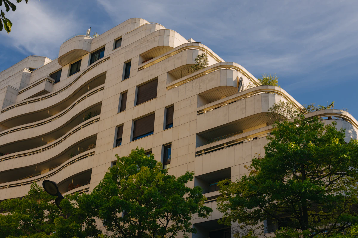 Gedung apartemen modern dengan balkon melengkung di bawah langit biru