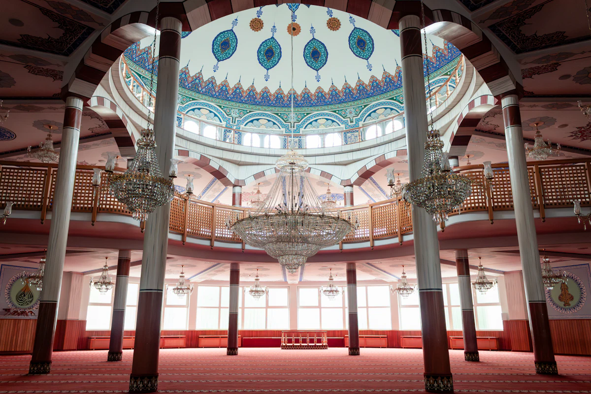 Interior masjid besar dengan lampu kristal dan pilar tinggi