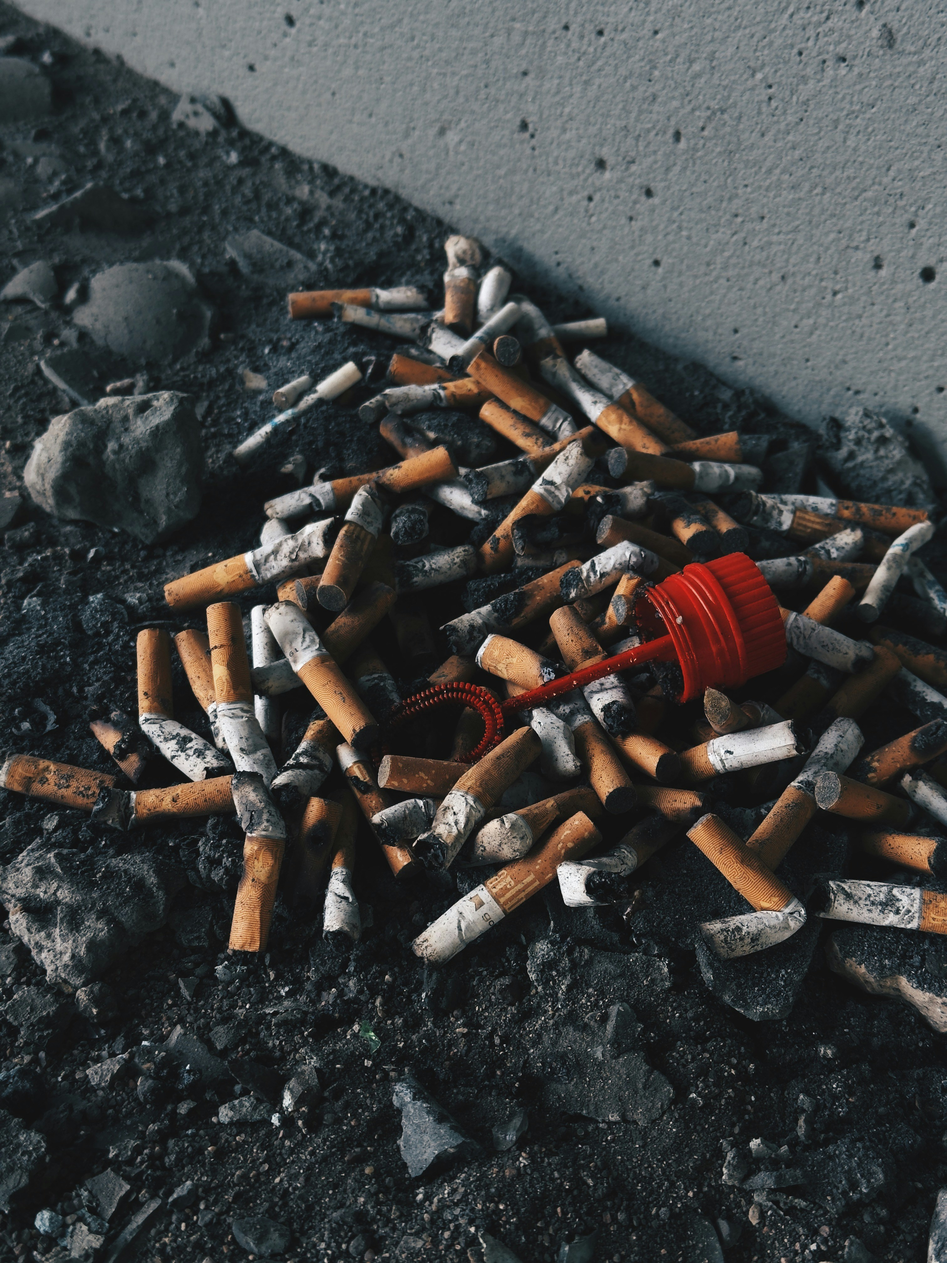 A pile of discarded cigarette butts and a red plastic bubble wand