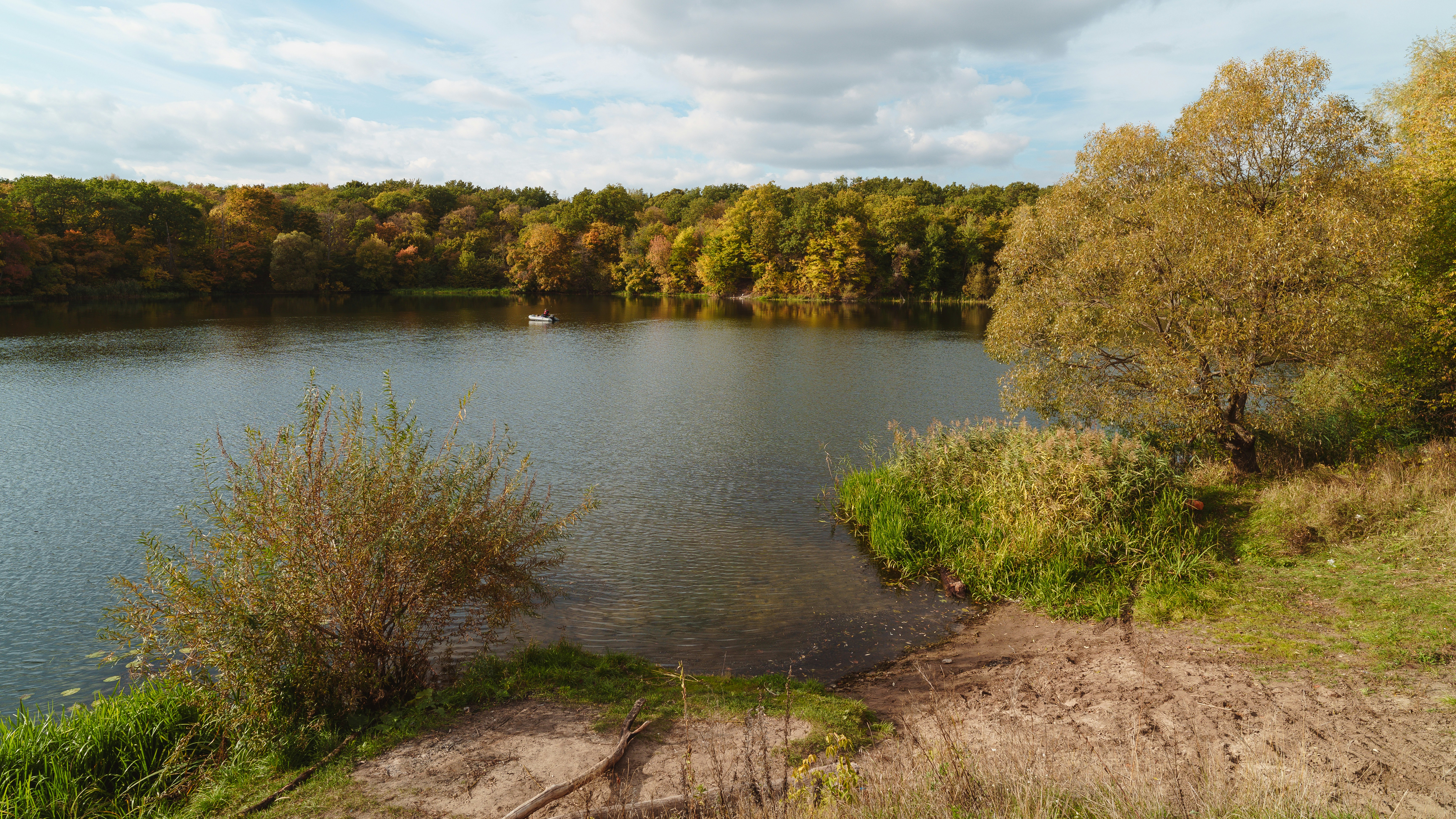 A small boat on a calm lake surrounded by autumn trees