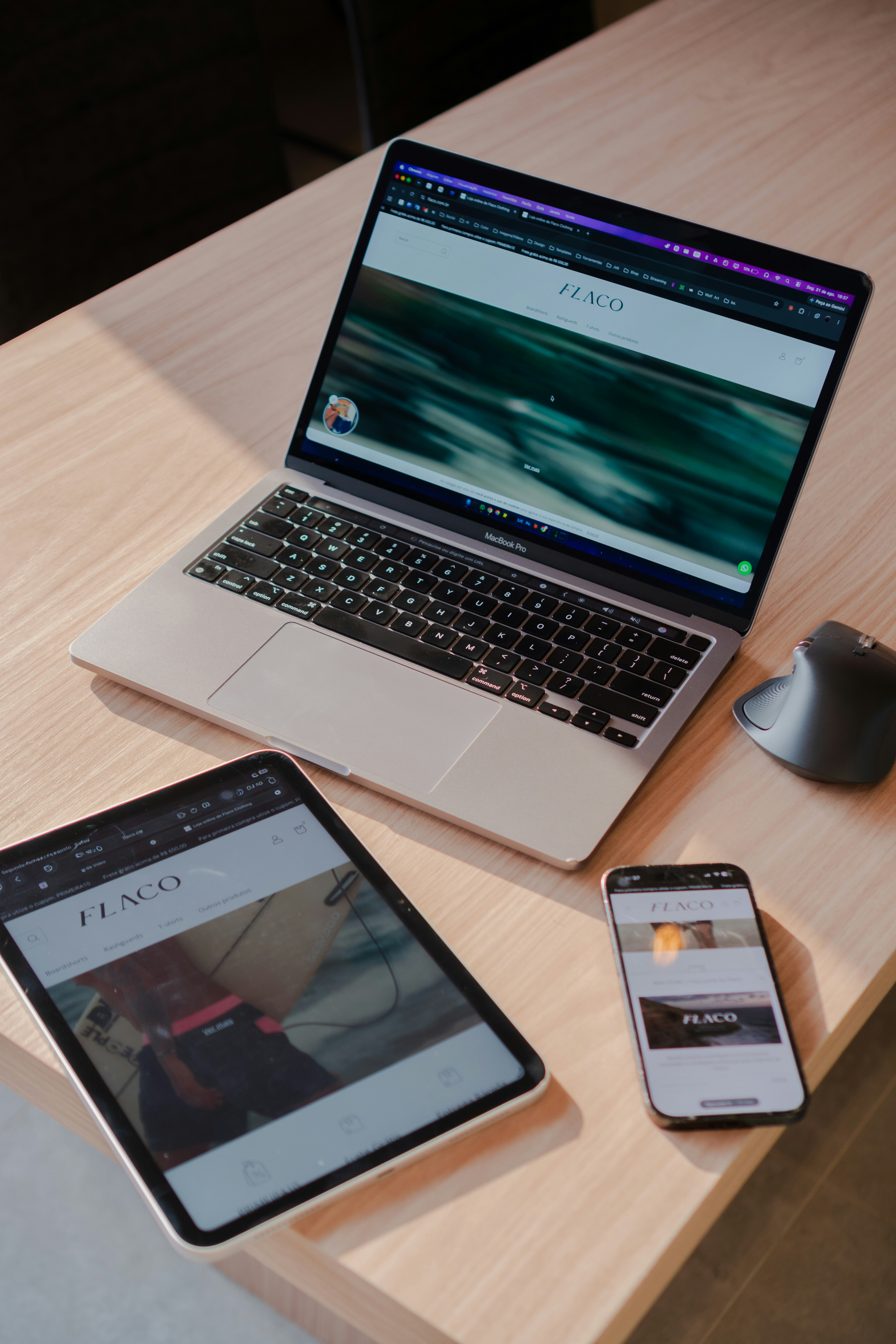 A laptop, tablet, and smartphone on a wooden desk in a home office