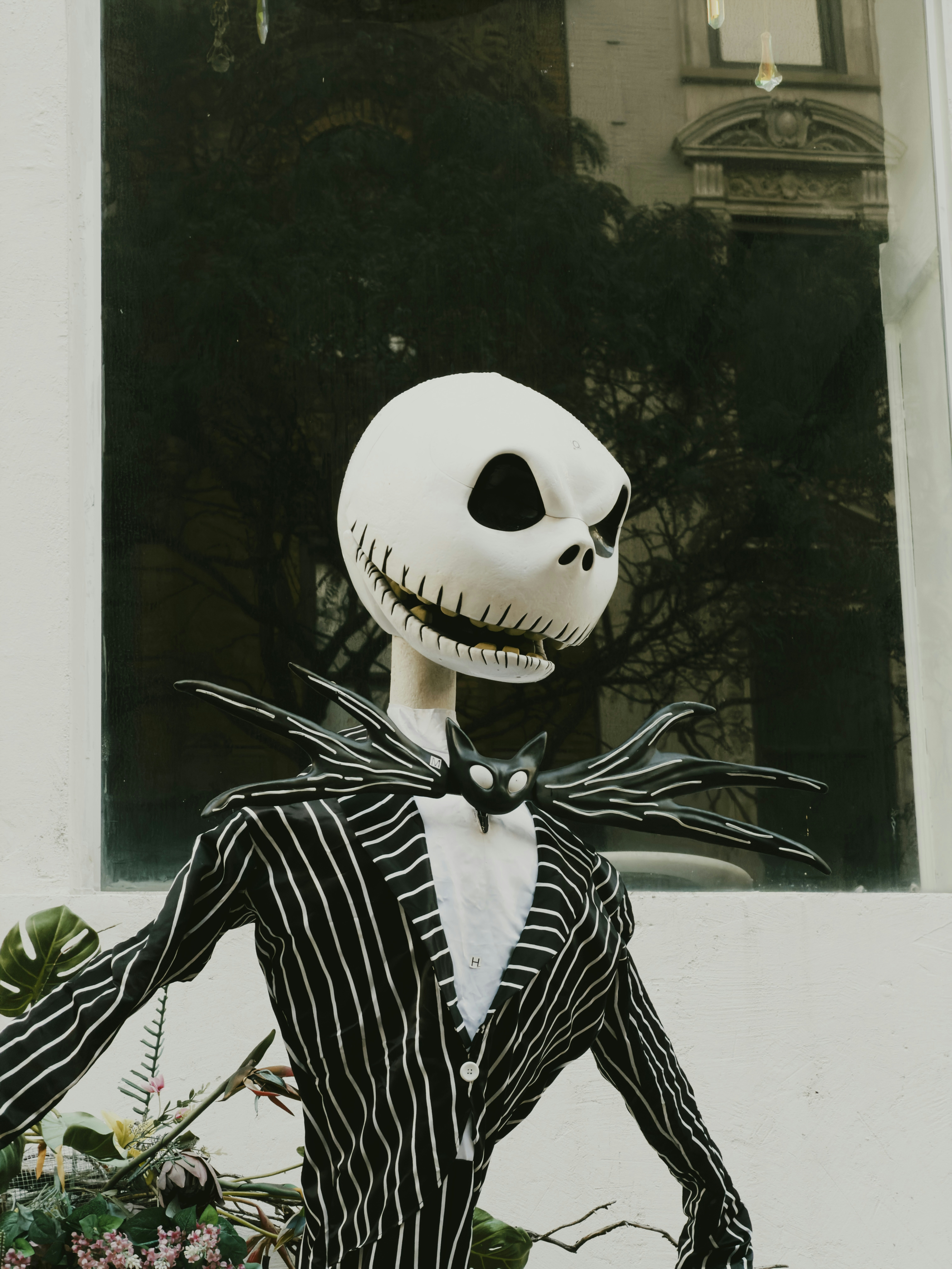 A Jack Skellington figure in a pinstriped suit standing before a window