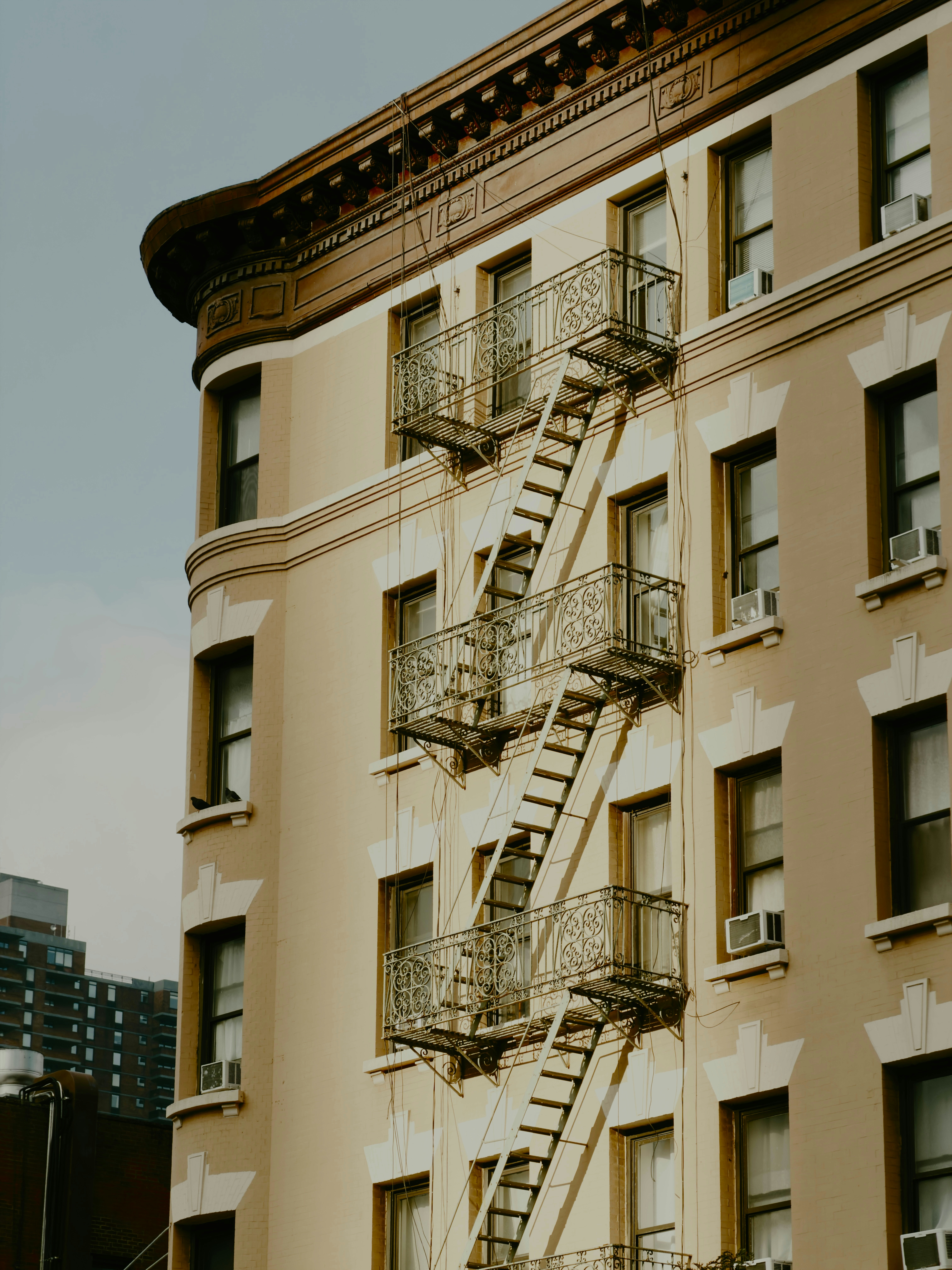 A tan apartment building with ornate metal fire escapes on the exterior facade