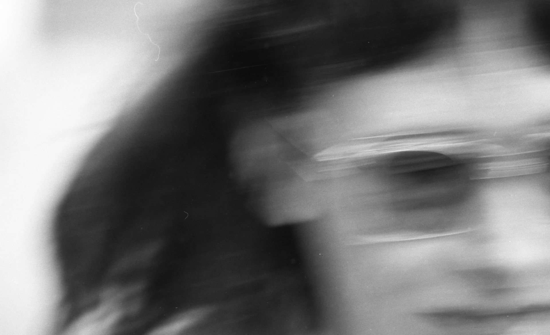 A person in sunglasses with hair blurred by heavy motion in black and white