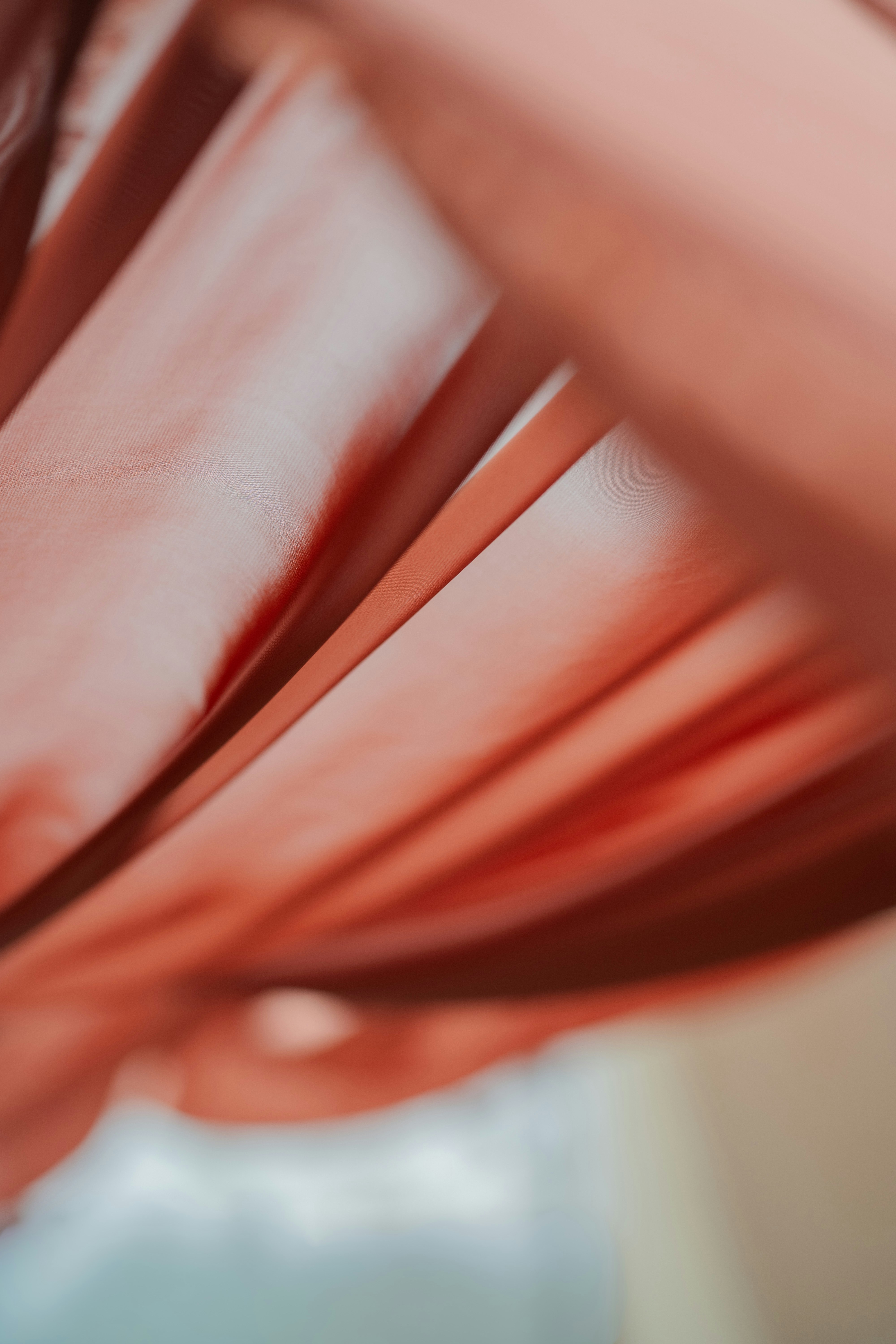 Close folds of smooth coral fabric with soft light and shadows